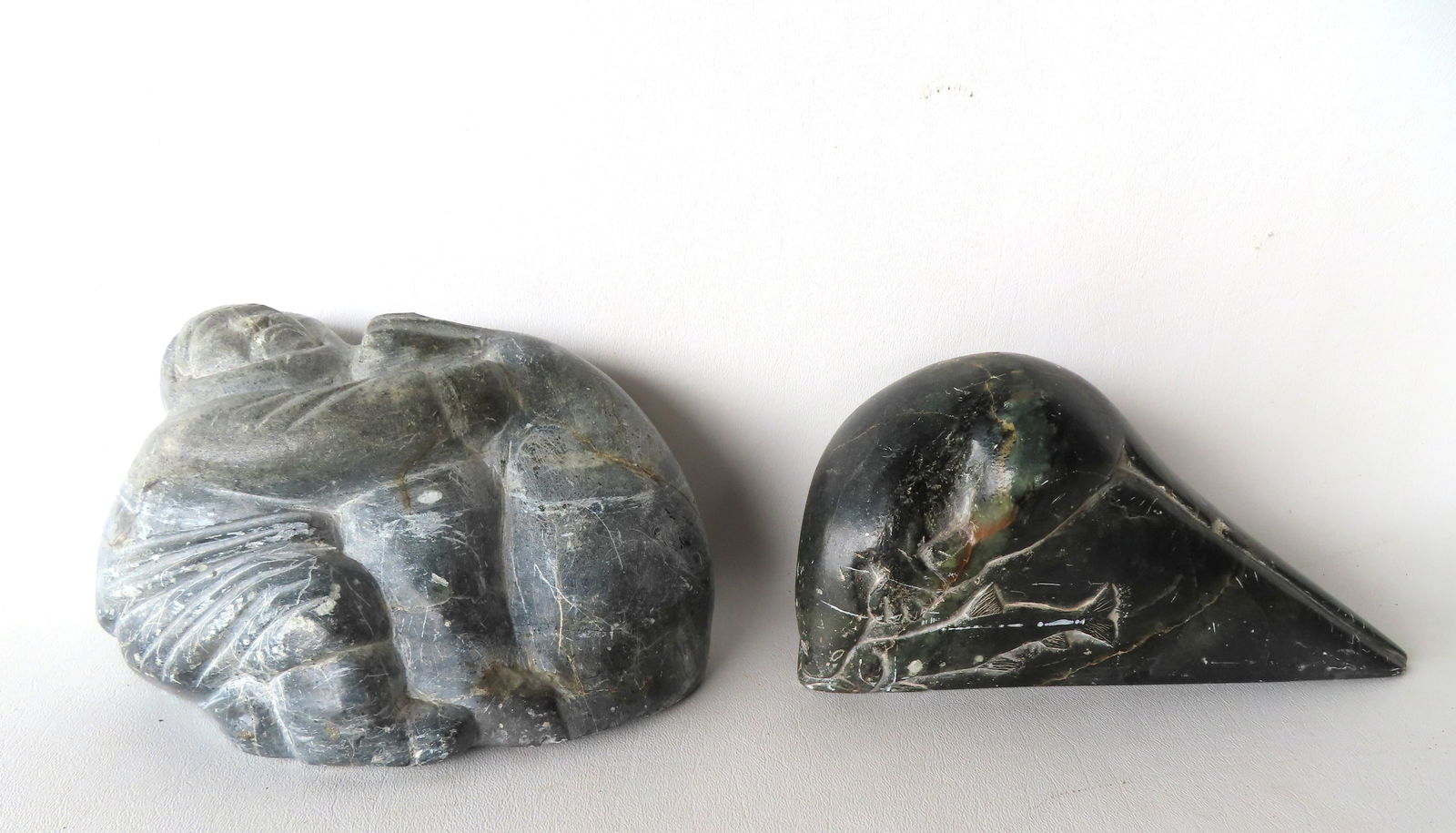 Two vintage Inuit stone carvings. The first, polished black stone sculpture of River Otter catching: Two vintage Inuit stone carvings. The first, polished black stone sculpture of River Otter catching salmon, signed Paulosie Sivuak (Inuit, 1930-1986) - measures 8 1/4"L x 3 1/2"W x 4 5/8"H - some surf