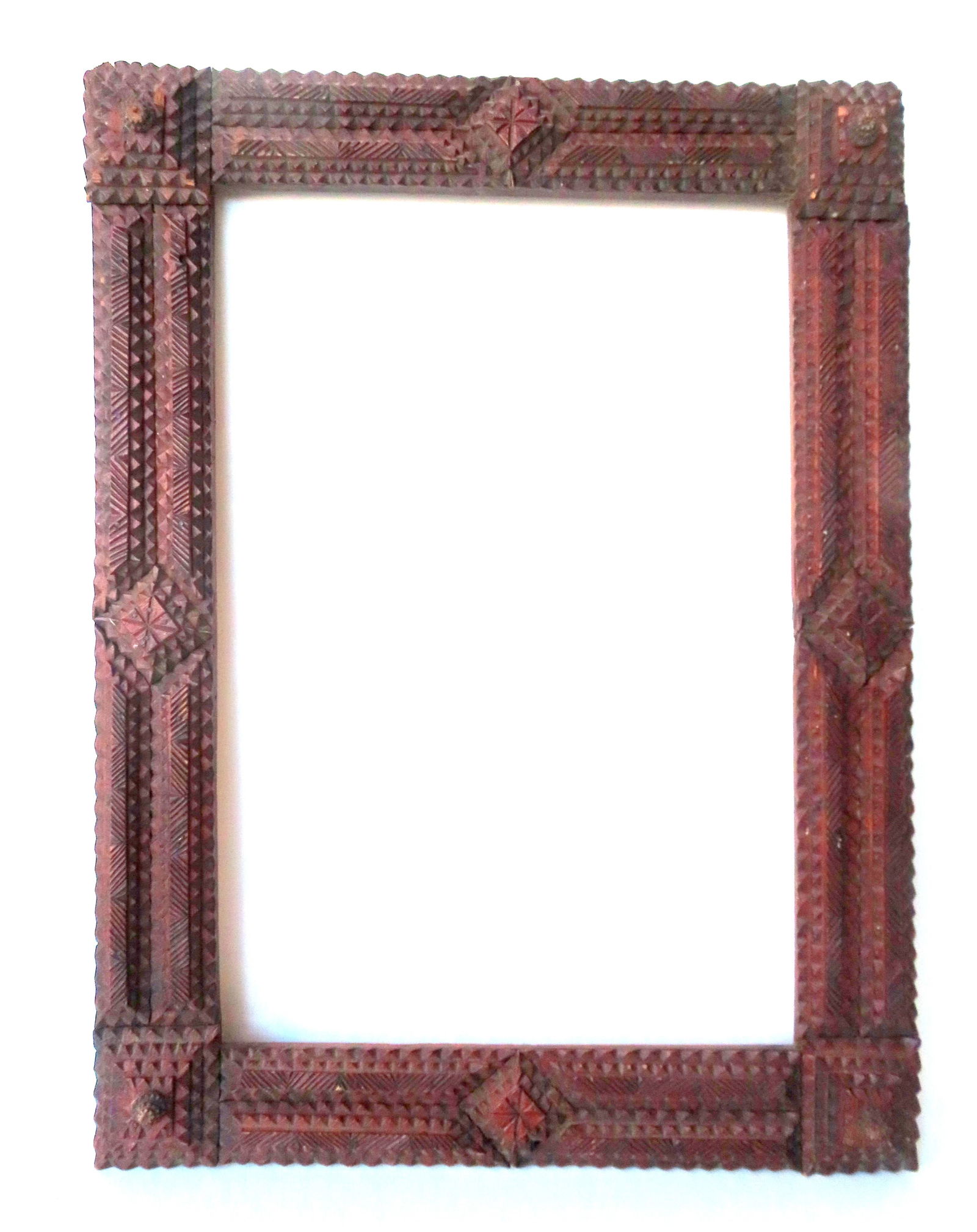 A very fine tramp art frame, with detailed surface carvings and having a small flower applied to the: A very fine tramp art frame, with detailed surface carvings and having a small flower applied to the top surface of each corner, 19th century. Overall size 17 1/2" x 23 1/8" and opening 12 7/8" x 20".