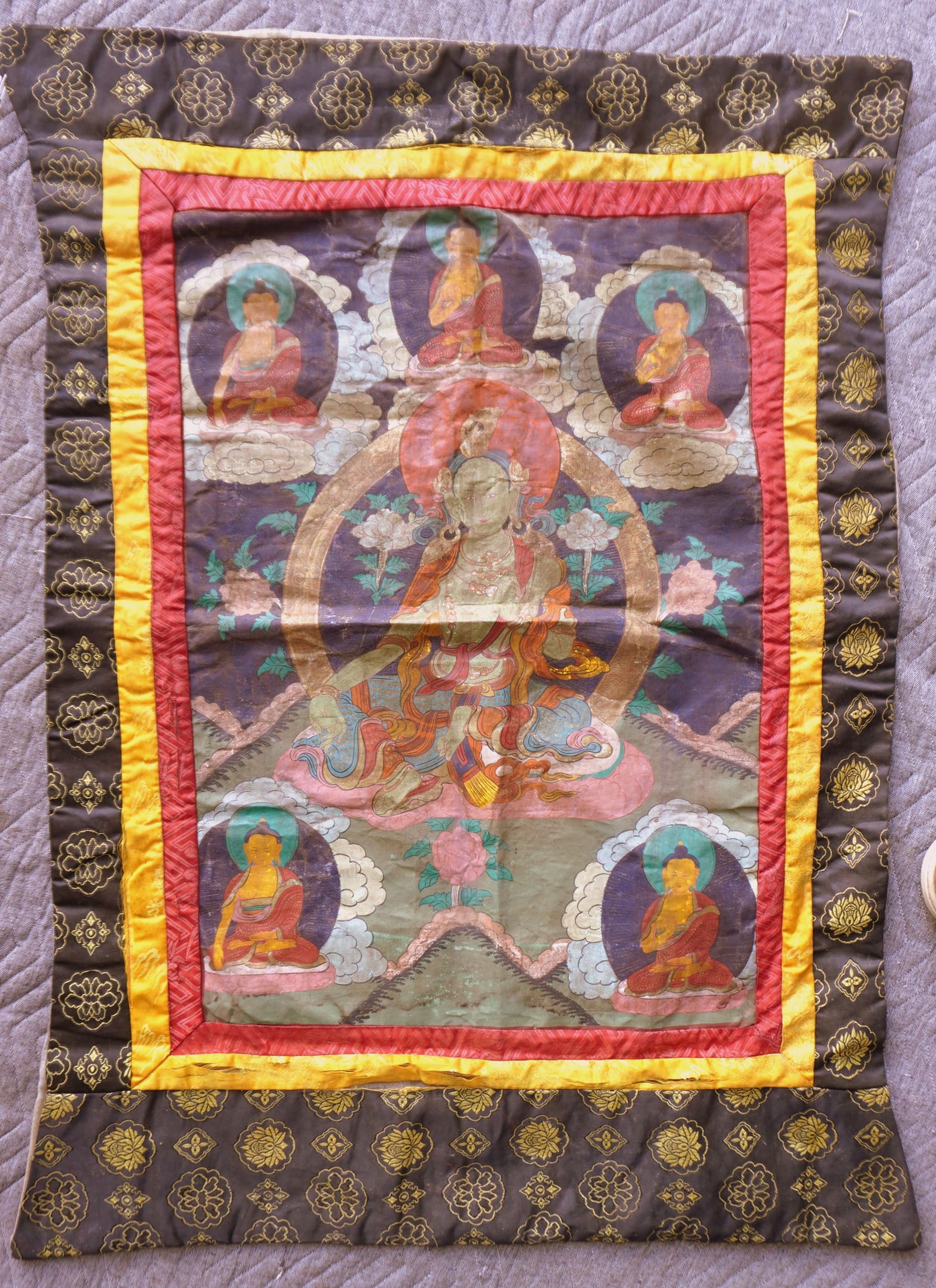 A Tibetan Thangka, hand painted with silk border, and having a central figure of Buddha (or other (1 of 9)