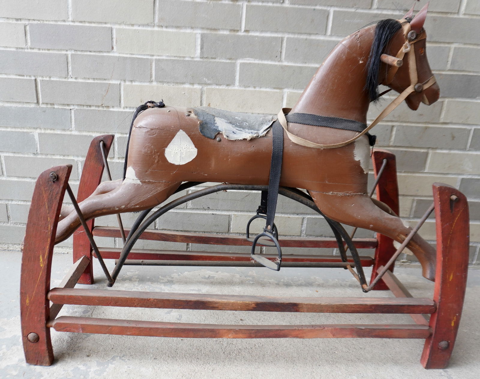 Carved wooden hobby horse in old brown paint with white splotches, mounted on wooden swivel base in (1 of 6)