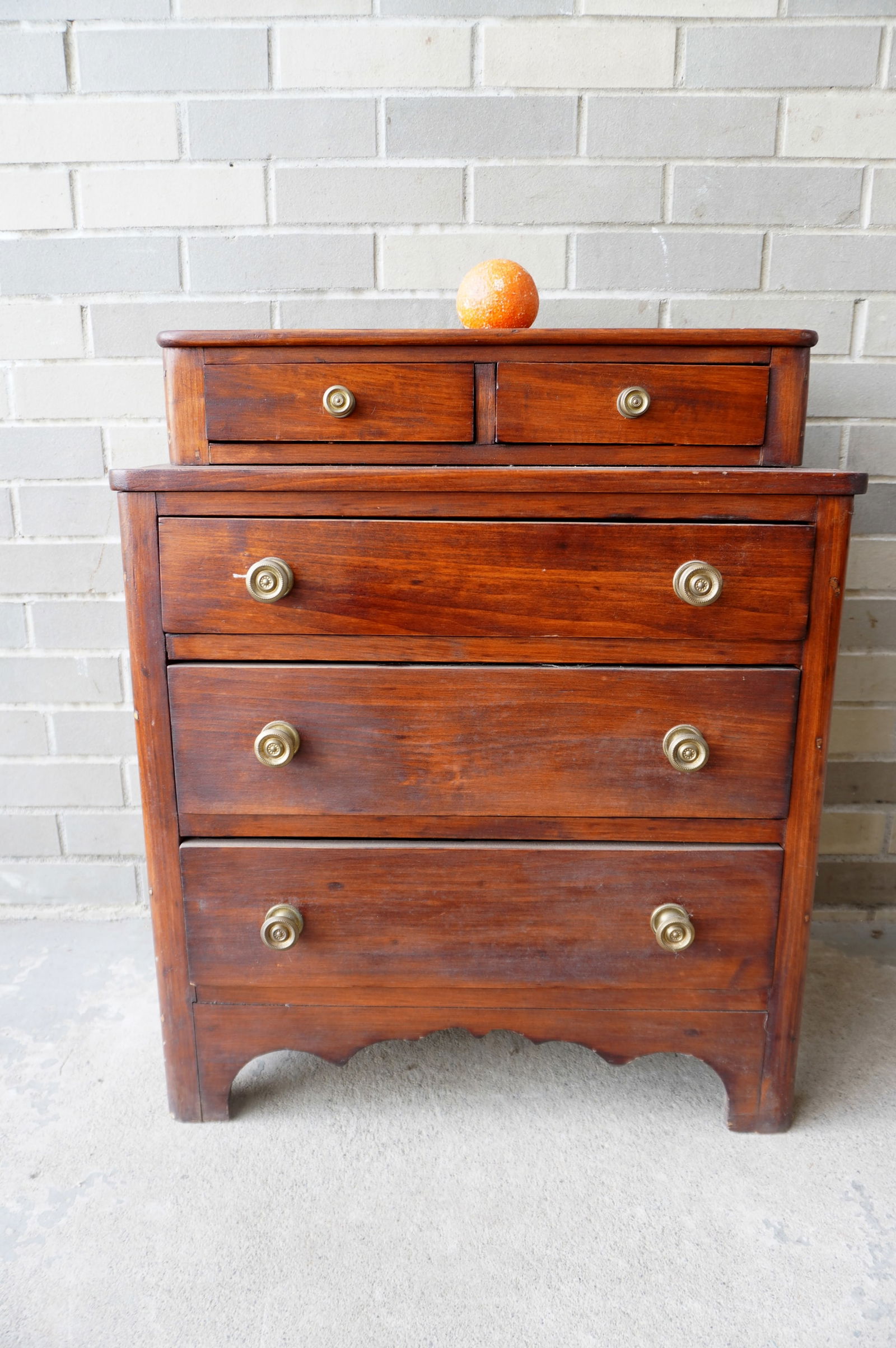 A child size Sheraton chest of drawers having 2 step-back drawers on top, over 3 graduated drawers: A child size Sheraton chest of drawers having 2 step-back drawers on top, over 3 graduated drawers on a very fine cutout base, circa 1820-40. The wood appears to be stained poplar or pine. All dovetai