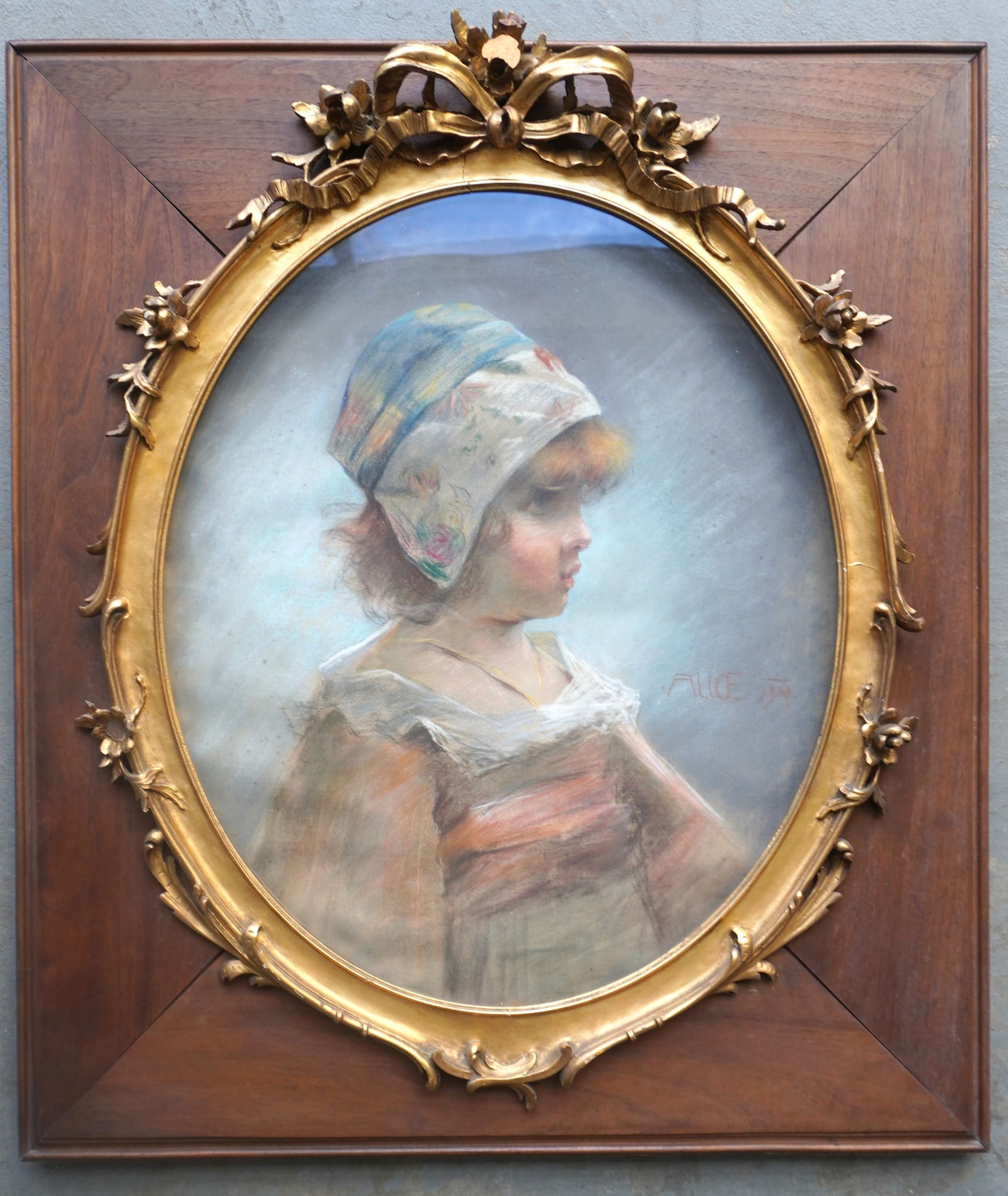 A beautiful late 19th c. pastel portrait of young girl wearing bonnet, housed in a very fine gilt: A beautiful late 19th c. pastel portrait of young girl wearing bonnet, housed in a very fine gilt gesso oval frame decorated with flowers and leaves, and inset within a rectangular walnut frame, signe