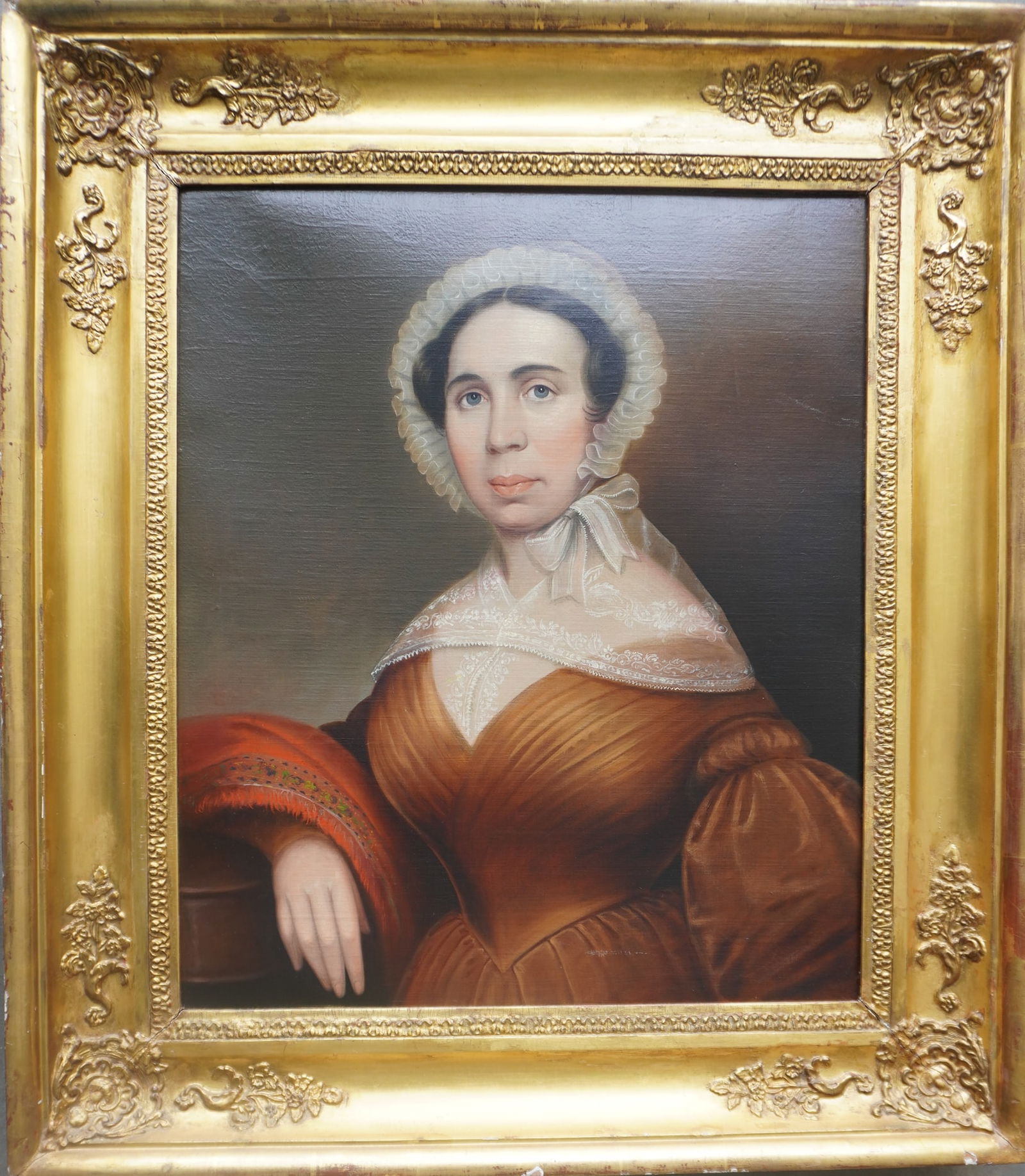 A very refined O/C Portrait of a lady wearing a bonnet, lace collar and a brown dress, early 19th: A very refined O/C Portrait of a lady wearing a bonnet, lace collar and a brown dress, early 19th century housed in a gilt gesso frame from the same period. The painting has been professionally cleane