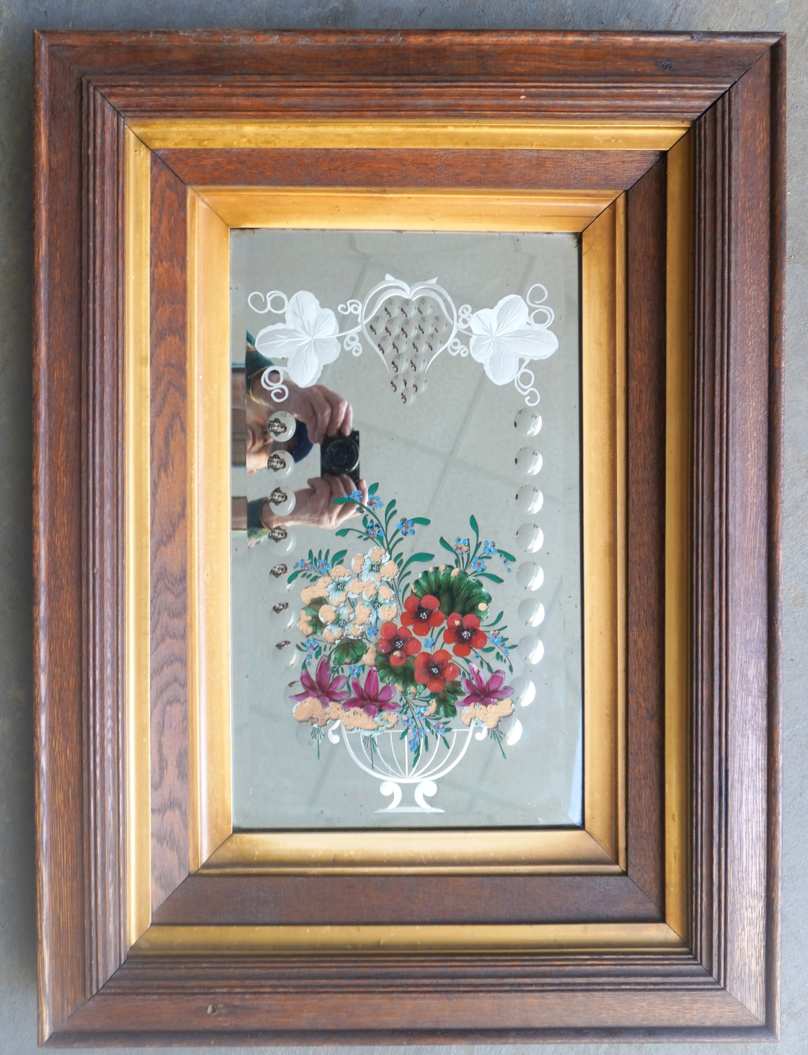 An etched and hand painted wall mirror decorated with hand painted flowers within an etched urn: An etched and hand painted wall mirror decorated with hand painted flowers within an etched urn under a small grape vine - some losses to paint, overall good condition, late 19th century, housed in or