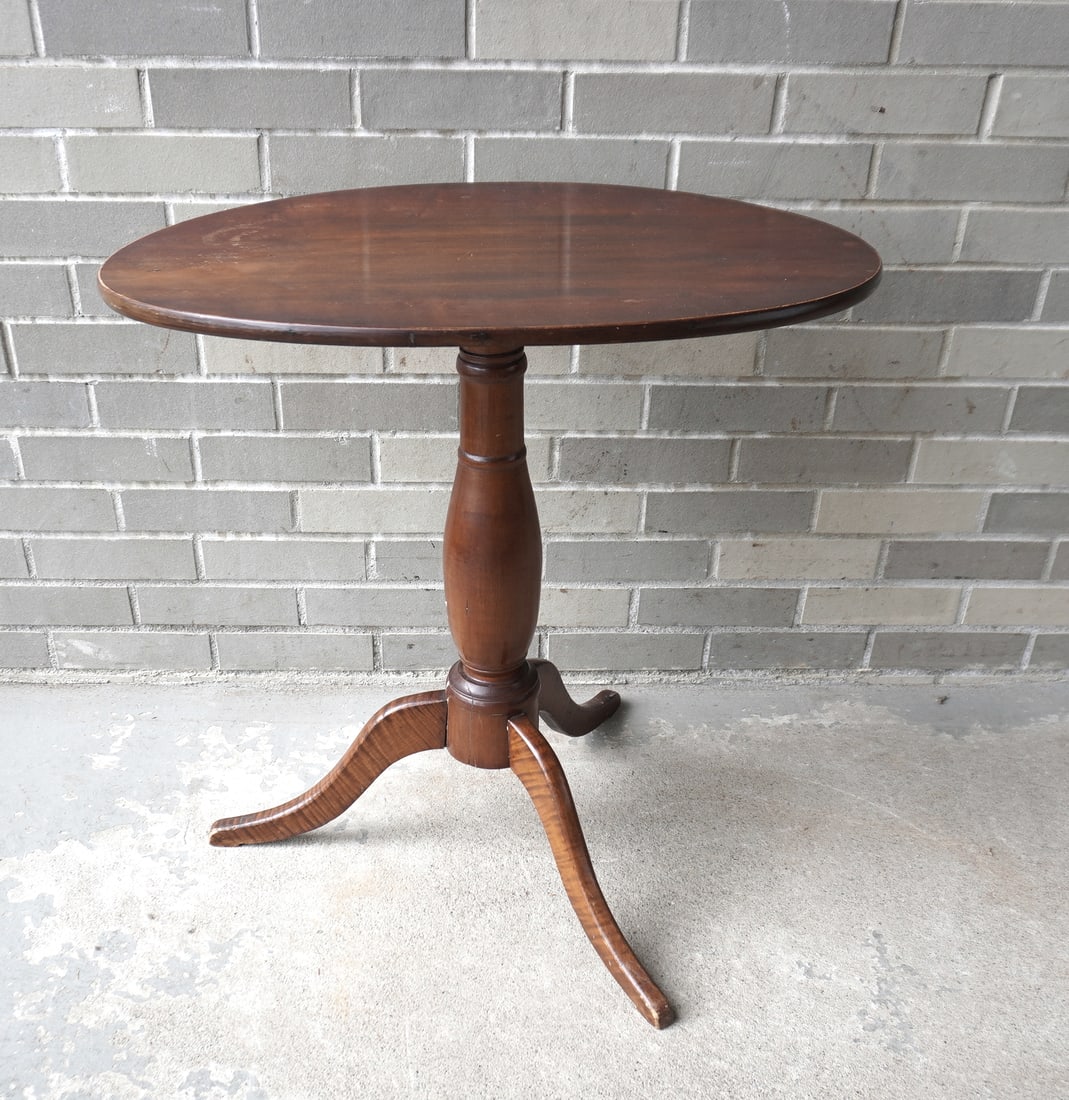 A good cherry snake foot tilt-top candlestand with oval top attached to turned column leading to: A good cherry snake foot tilt-top candlestand with oval top attached to turned column leading to tri-leg tiger maple feel, circa 1800 in very good condition. Measures 25 7/8"W x 17 1/4"W x 26 1/2"H.