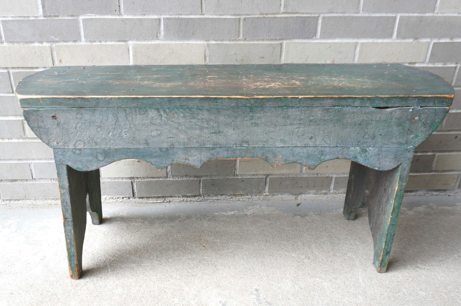 A country pine bench in original blue-green paint, mid 19th century, square nail construction,: A country pine bench in original blue-green paint, mid 19th century, square nail construction, shaped apron and splayed legs. Measures 37"L x 11"D x 17 5/8"H. Missing a small section in the center of