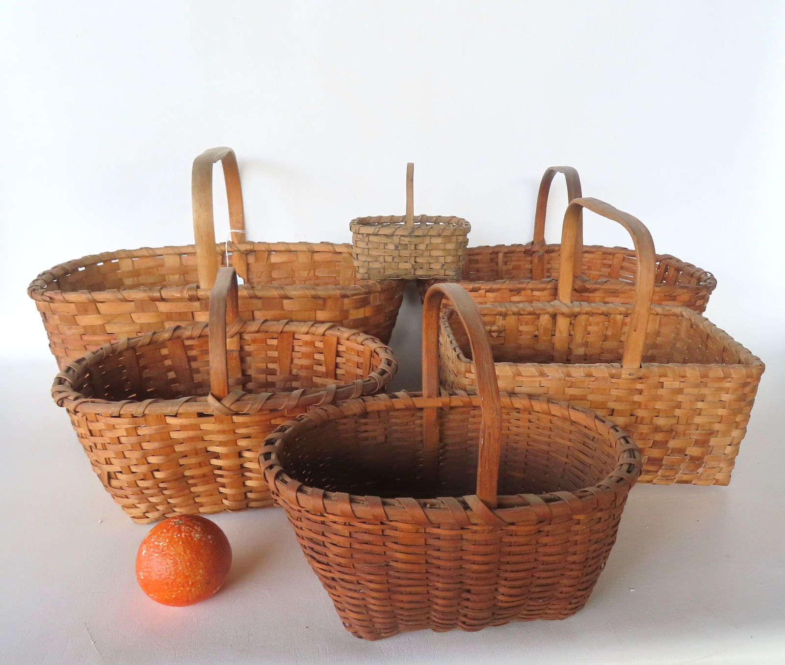 Grouping of 6 woven splint baskets with a single overhead looped handle, 19th century. Most in very (1 of 20)