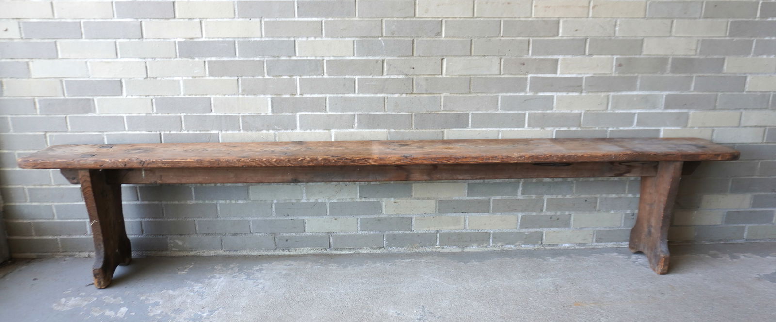 A long pine bench with shaped sides/legs mortised through top, see-through construction. Measures: A long pine bench with shaped sides/legs mortised through top, see-through construction. Measures 8'L x 10 1/2"W x 18 1/4"H - the top wooden plank is 1 1/2" thick so it has not sagged and is in good o