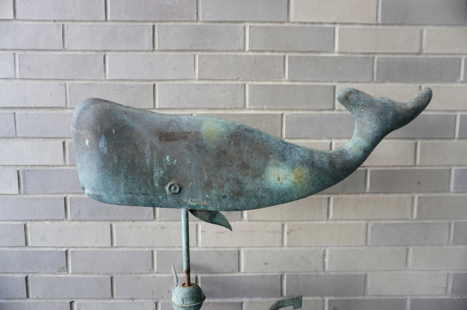 A copper whale weathervane with directional and mounting pole, circa 1950-1970. Missing one fin on: A copper whale weathervane with directional and mounting pole, circa 1950-1970. Missing one fin on the whale's side, small impression on side of head of the whale, hardly noticeable, otherwise good co