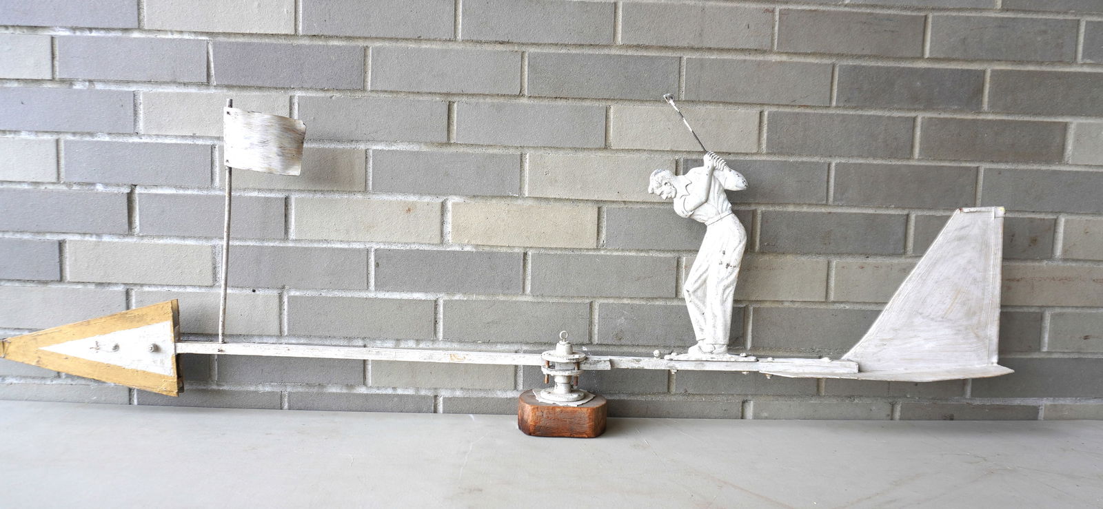 An unusual painted aluminum weathervane depicting a golfer with club ready to strike a golf ball: An unusual painted aluminum weathervane depicting a golfer with club ready to strike a golf ball mounted on a long arrow shaped rod with flagstick mounted near tail of vane, original white paint with