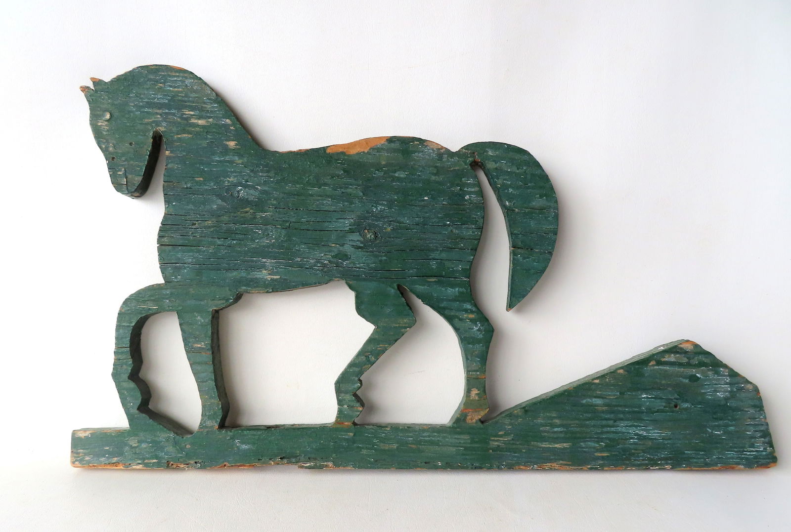 A primitive prancing horse silhouette wooden weathervane in old green paint, 19th century. Extensive: A primitive prancing horse silhouette wooden weathervane in old green paint, 19th century. Extensive weathering, other paint noticeable under the green paint - missing shaft - overall good condition.