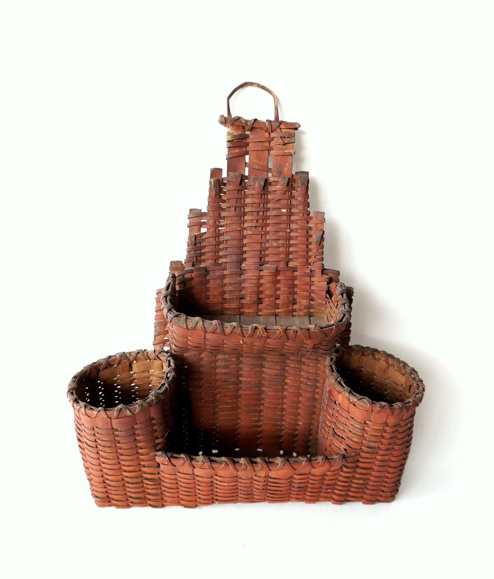 An very fine primitive woven splint kitchen wall pocket basket in original dry red paint, probably: An very fine primitive woven splint kitchen wall pocket basket in original dry red paint, probably Native American, circa 1800. The upper pocket has a splint break on each side where it meets the step
