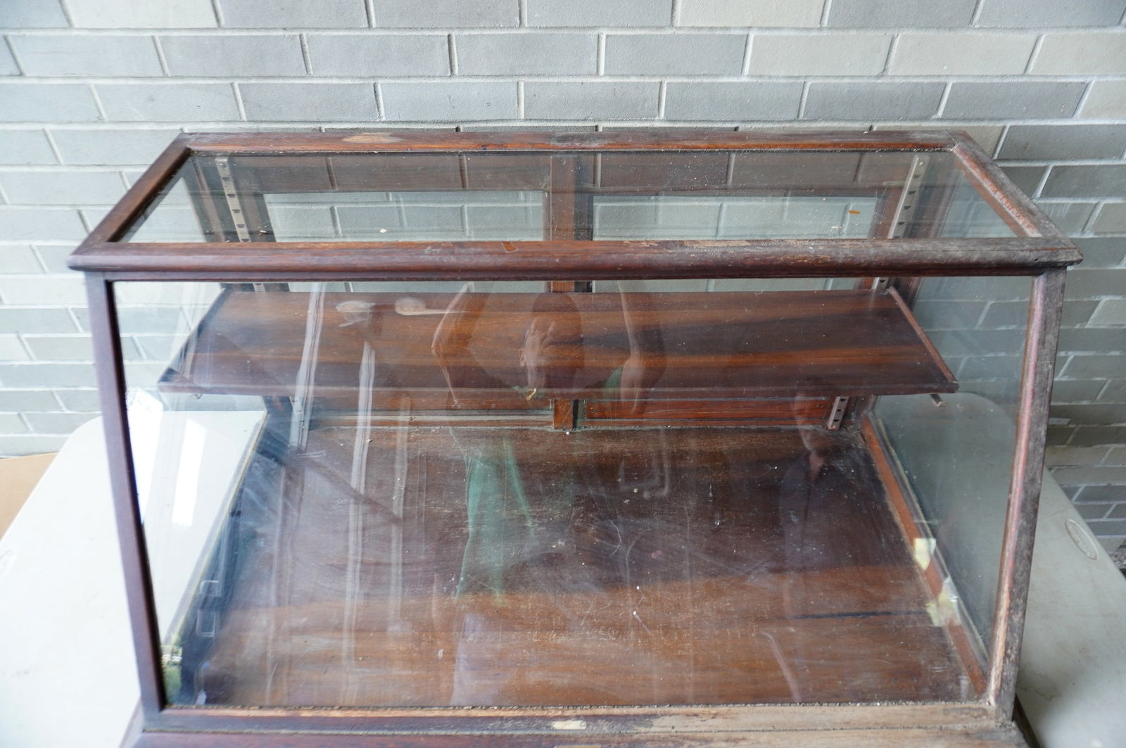 A country store table top slant front oak showcase with sliding rear doors and single shelf signed: A country store table top slant front oak showcase with sliding rear doors and single shelf signed "The Sun Mfg. Co. / Columbus Ohio" - Very good original condition, circa 1900. Measures 47 3/4"W x 25