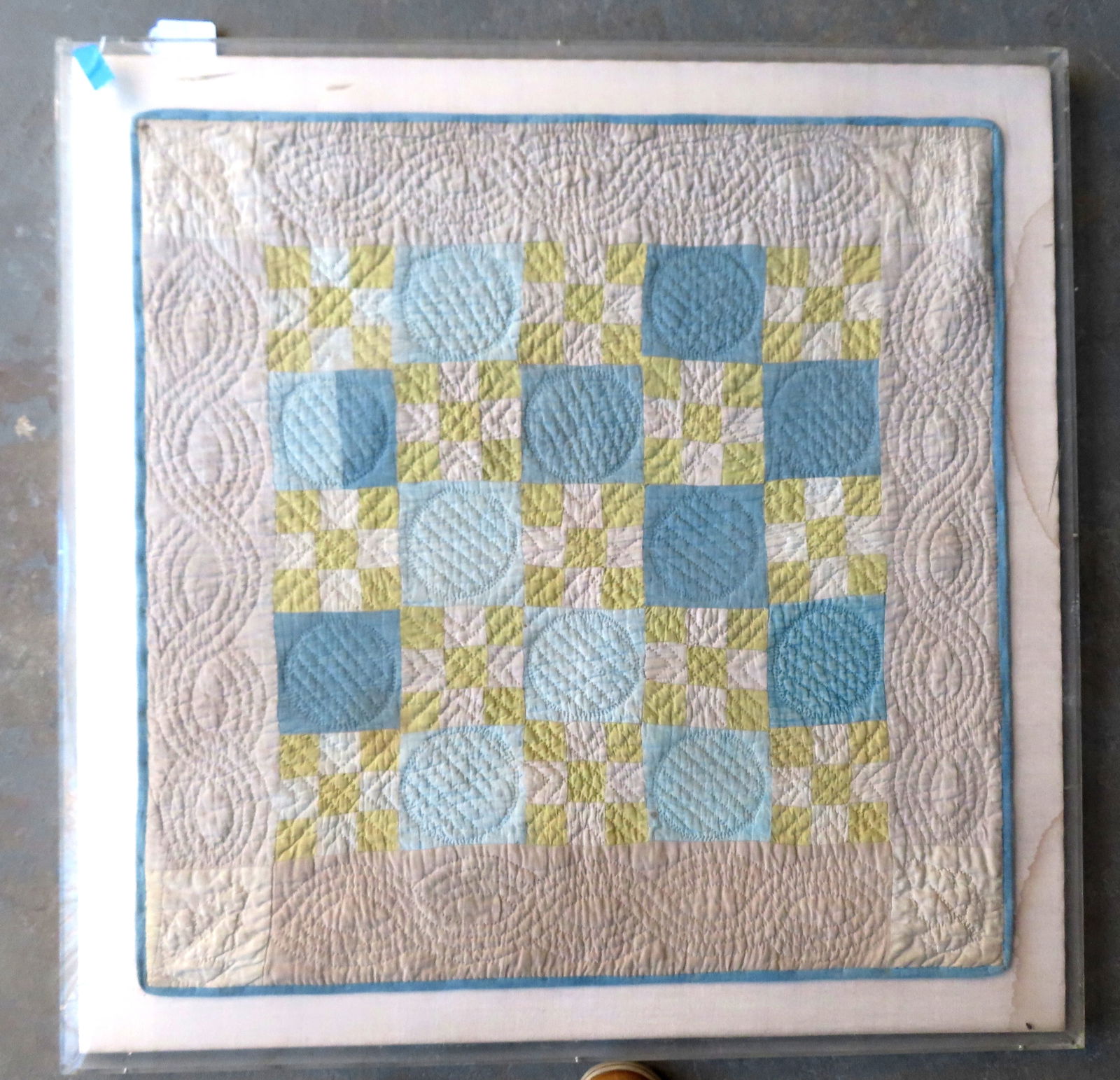 A mounted hand sewn crib quilt in the NY State 9-patch variation pattern. Housed within a plexiglass (1 of 8)
