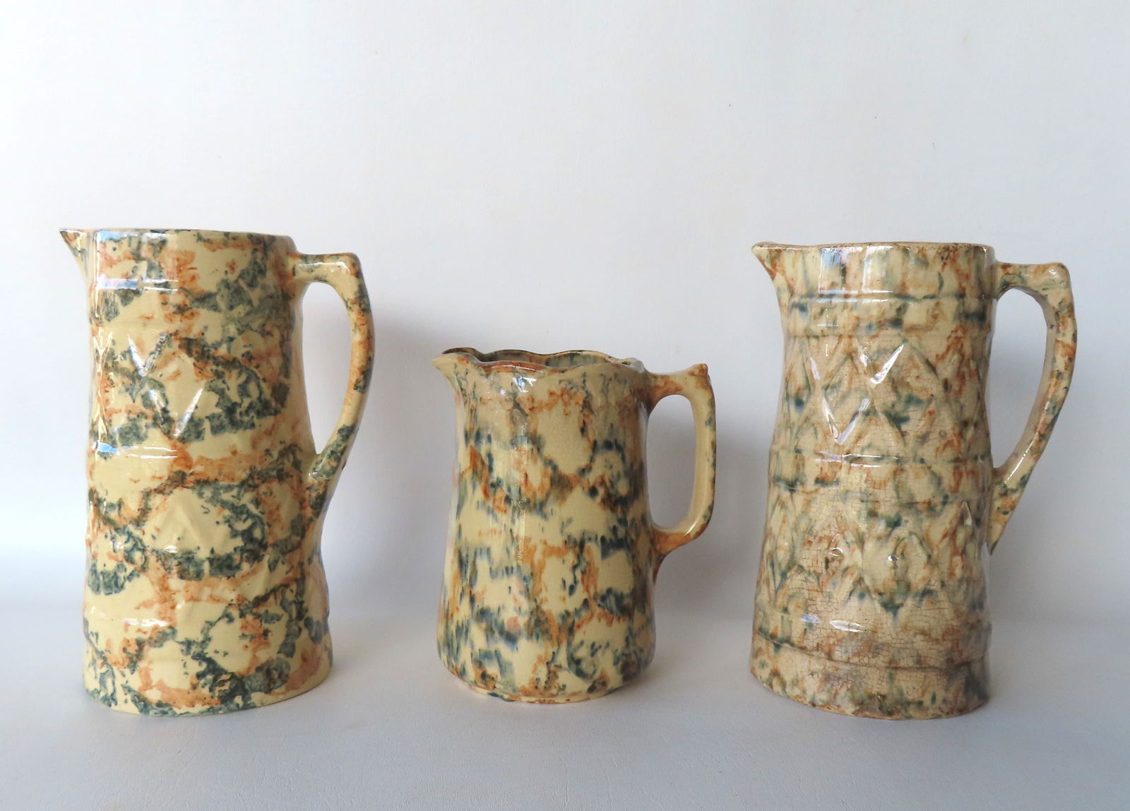 Three multi-colored spongeware pitchers and a redware mixing bowl, all 19th century. The 2 tallest (1 of 5)