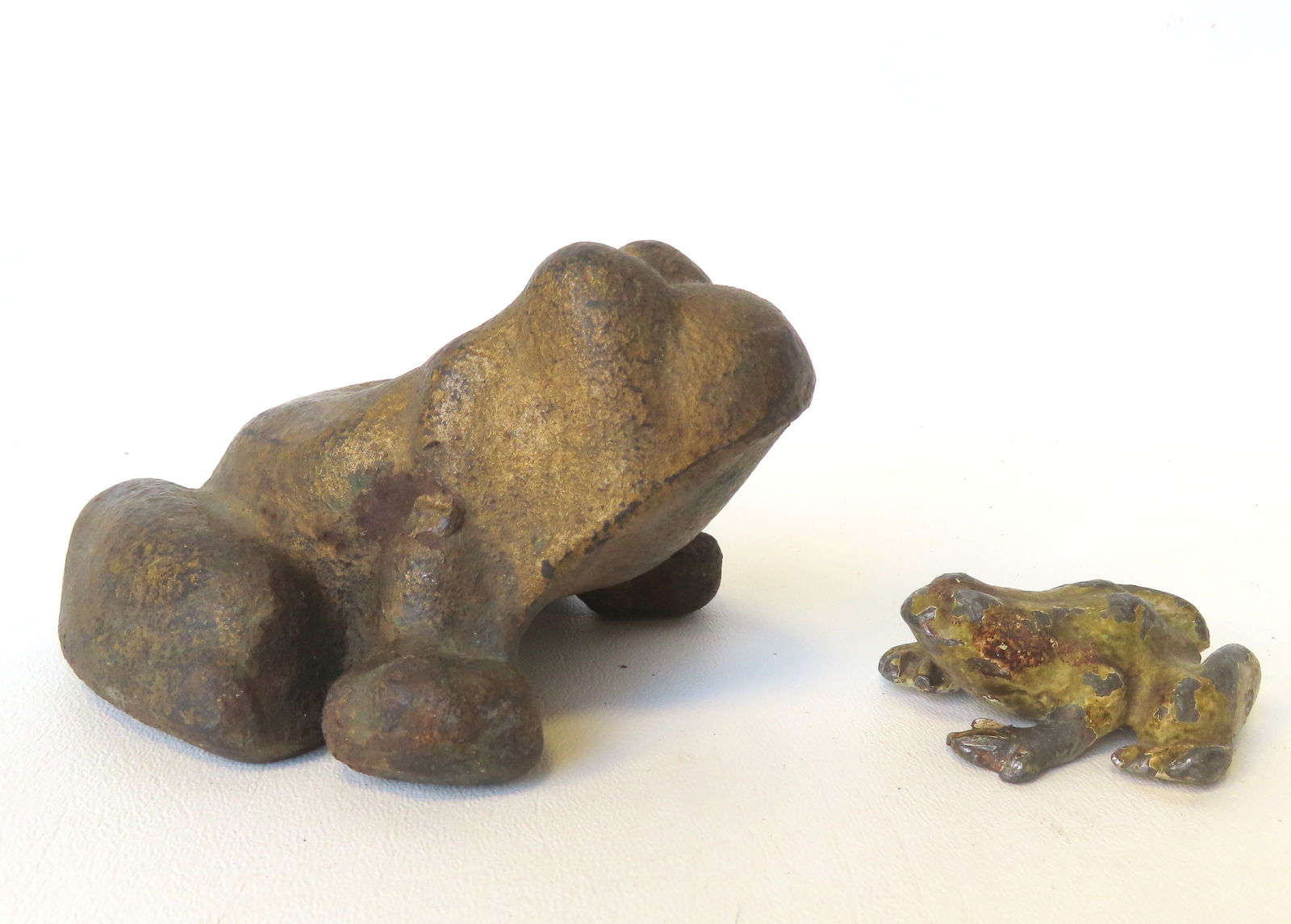 Two metal frogs. The first, a heavy cast iron frog door stop in original green - slightly worn paint: Two metal frogs. The first, a heavy cast iron frog door stop in original green - slightly worn paint but overall good condition - late 19th to early 20th century - measures 5 1/2"D x 4 1/4"W x 3"H; an