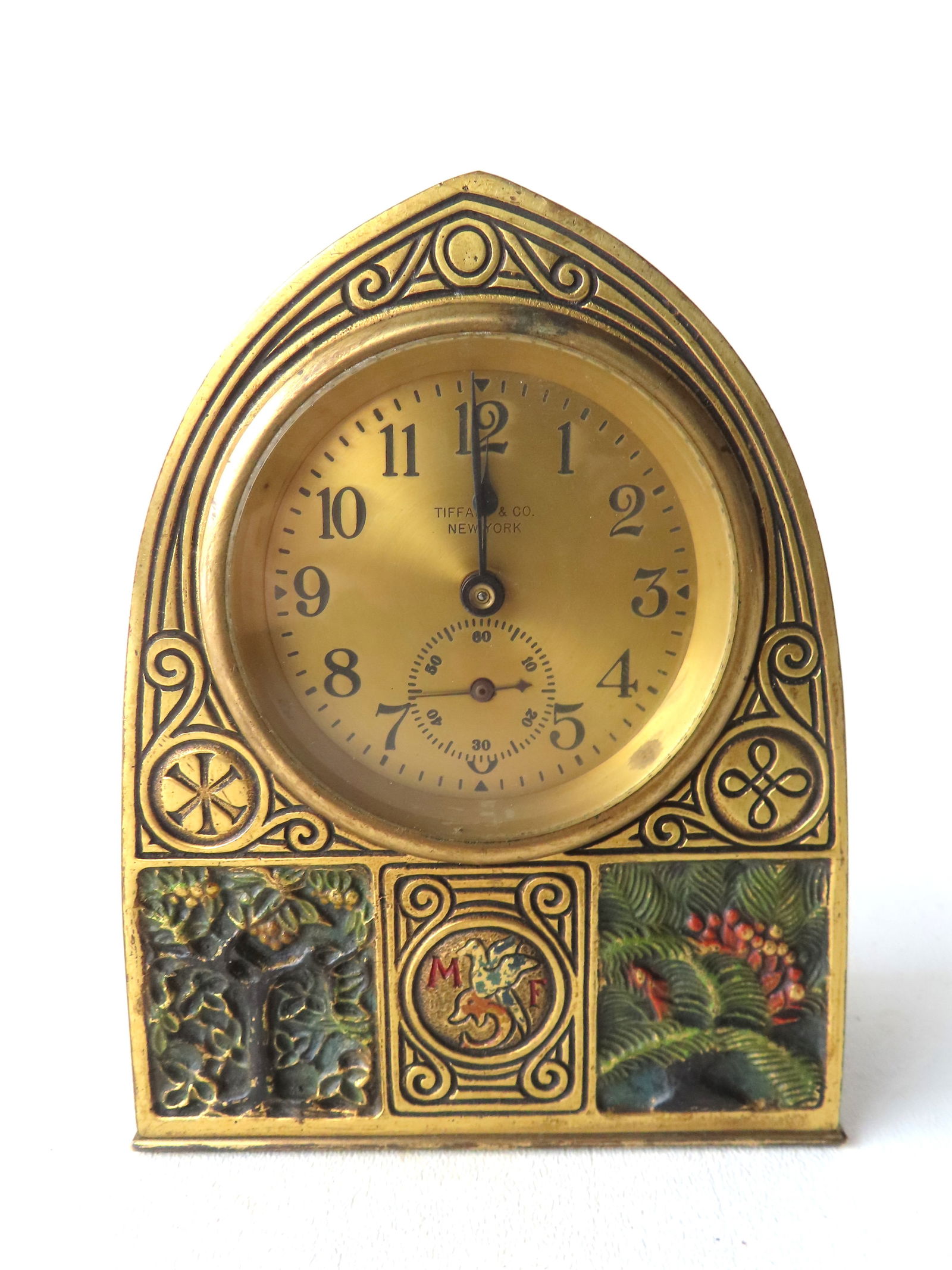 Tiffany Studios gilt bronze coal-painted desk clock in the Bookmark pattern with arched top, marked: Tiffany Studios gilt bronze coal-painted desk clock in the Bookmark pattern with arched top, marked on door "Tiffany Studios / New York / 1857" (1857 being the model number) - the face with Arabic num