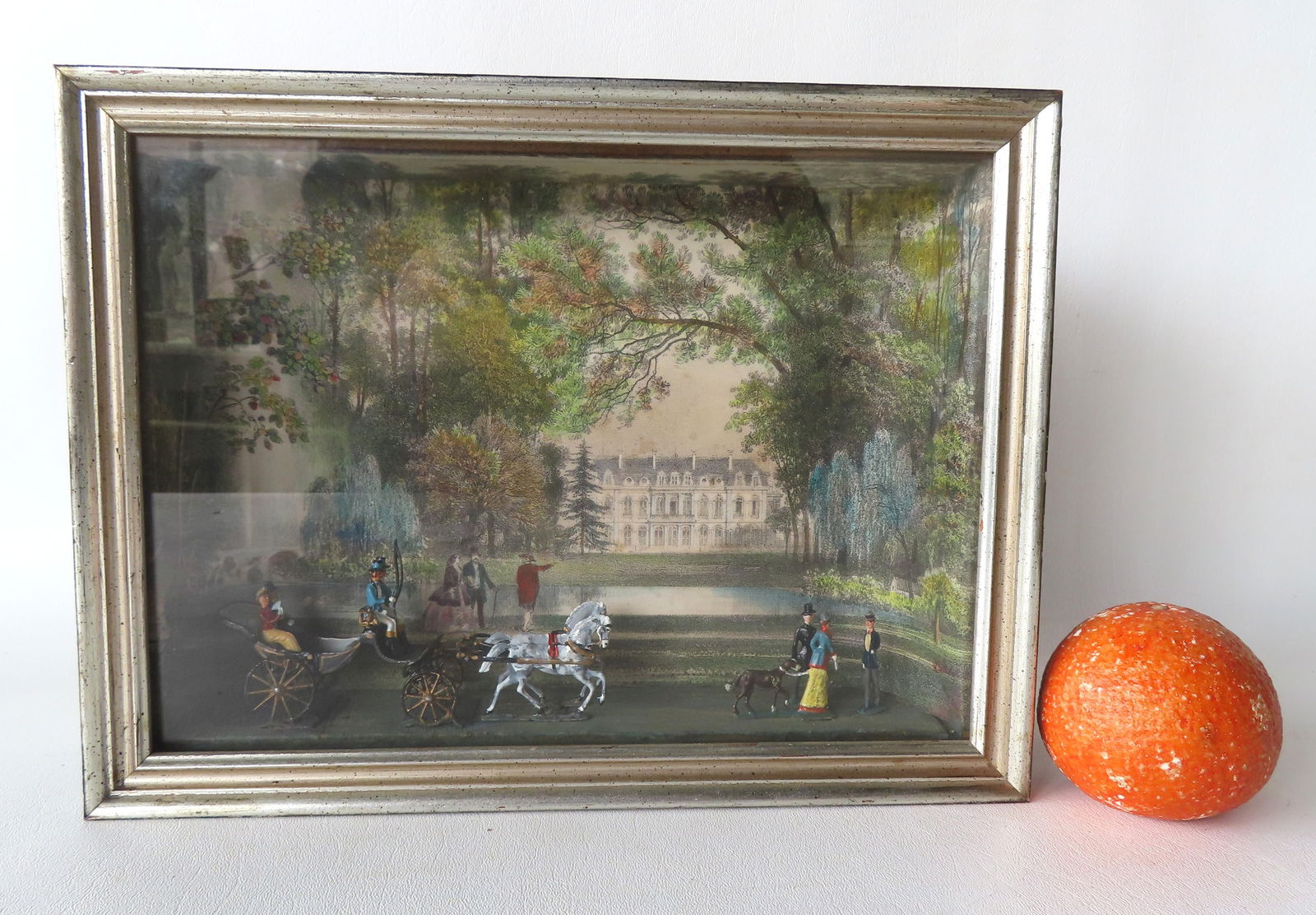 A diorama depicting a historical French scene, with a hand colored lithograph of a French palace in: A diorama depicting a historical French scene, with a hand colored lithograph of a French palace in the background and hand painted lead figures of a horse drawn carriage and other figures including l