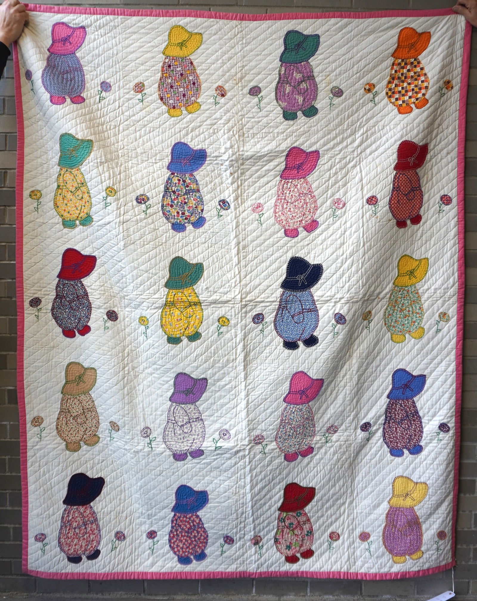 An applique quilt in the Sunbonnet Baby pattern depicting Sunbonnet Babies walking between applique: An applique quilt in the Sunbonnet Baby pattern depicting Sunbonnet Babies walking between applique flowers, circa 1930 - all hand sewn quilting and hand sewn applique, but with machine stitched borde