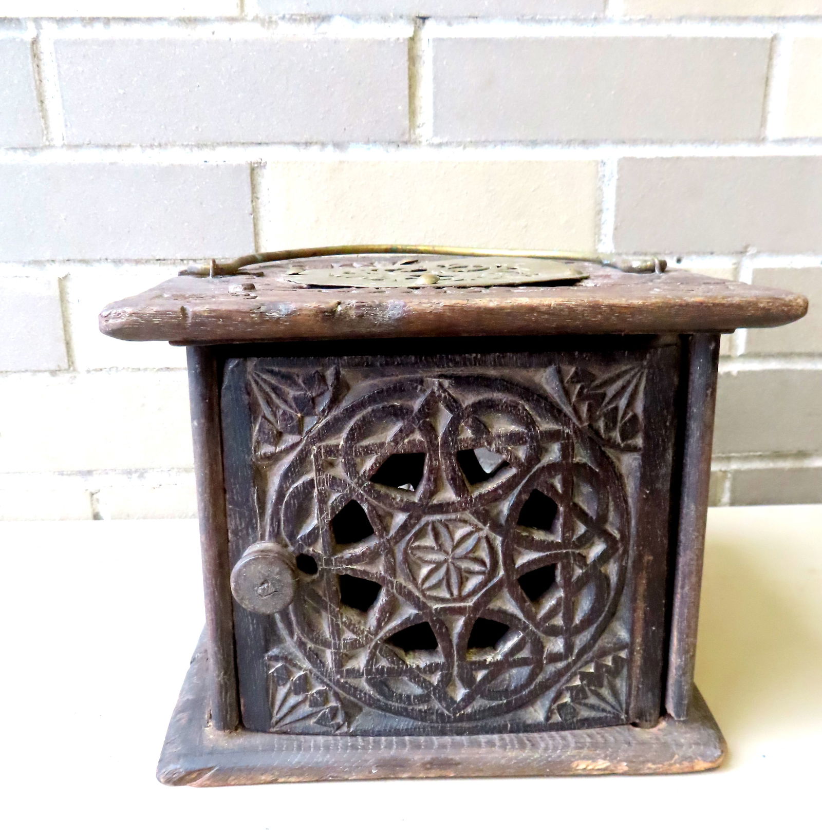 A primitive hand carved oak foot warmer, profusely carved with open work designs on sides and lid, m: A primitive hand carved oak foot warmer, profusely carved with open work designs on sides and lid, 18th century. Condition: The top with an attached 19th/20th century reticulated brass cover to hide b