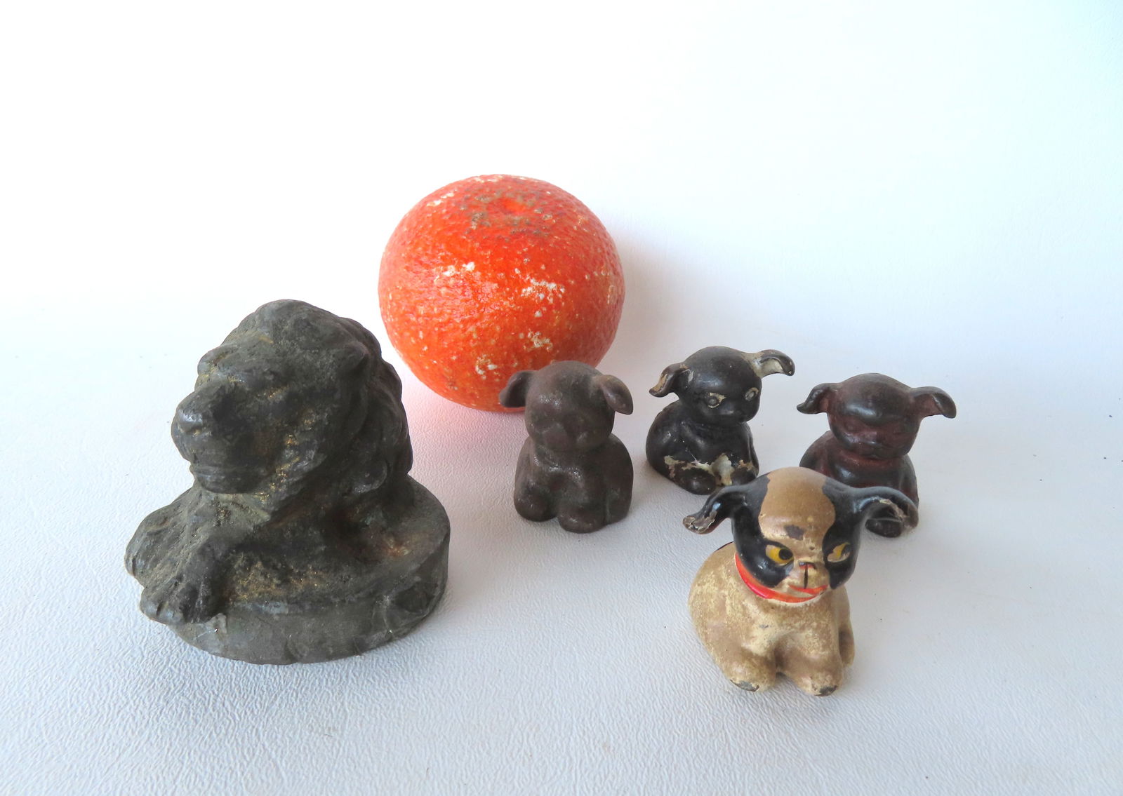 Grouping of 4 miniature cast iron dog figures, including 2 advertising "Bucki Carbon Ribbon", probab: Grouping of 4 miniature cast iron dog figures, including 2 advertising "Bucki Carbon Ribbon", probably paper weights, together with a lead lion's head paper weight, traces of original gold paint - thi