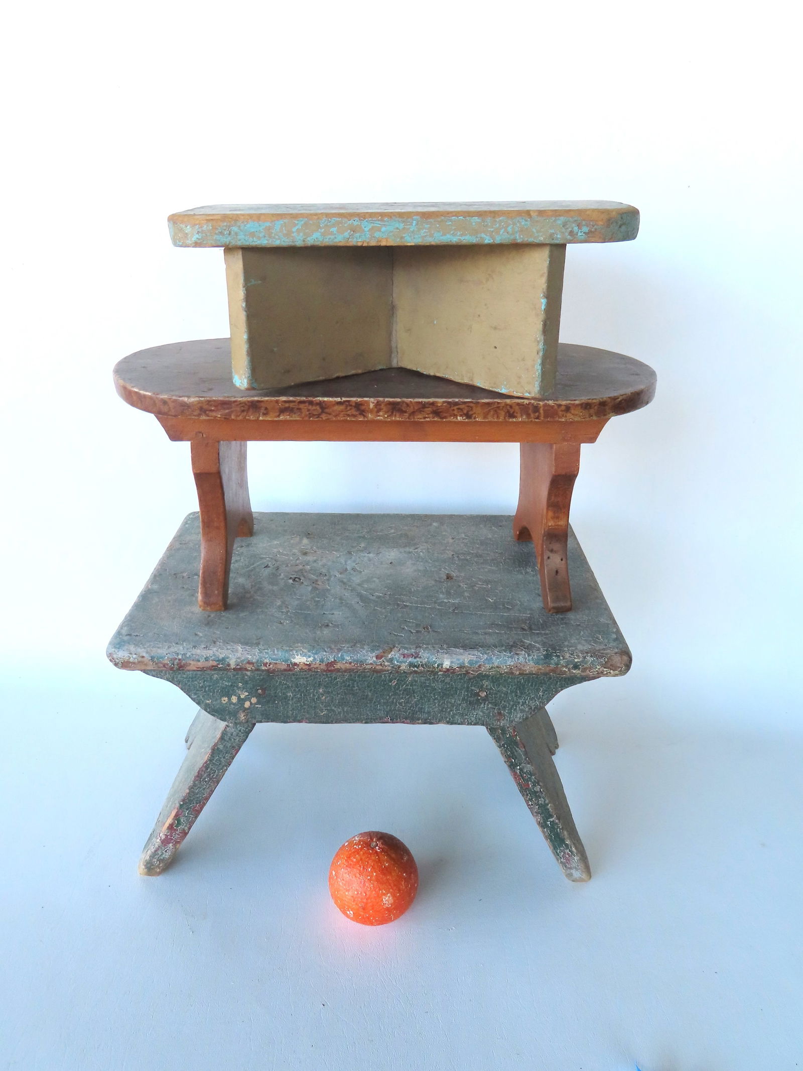 Three primitive cricket stools in old paint, all 19th century in good structural condition. The firs: Three primitive cricket stools in old paint, all 19th century in good structural condition. The first, with splayed legs, shaped apron and sides and having layers of old paint, 1850 or earlier - this