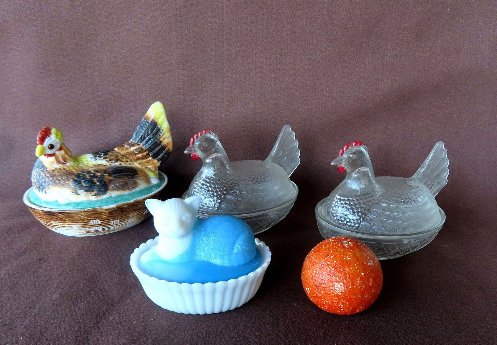 A grouping of 4 figural hen on nest and resting cat covered dishes, typically used for holding eggs,: A grouping of 4 figural hen on nest and resting cat covered glass dishes, typically used for holding eggs, nuts, candy and the like. Includes 2 hens in colorless glass with painted red combs, a colorf