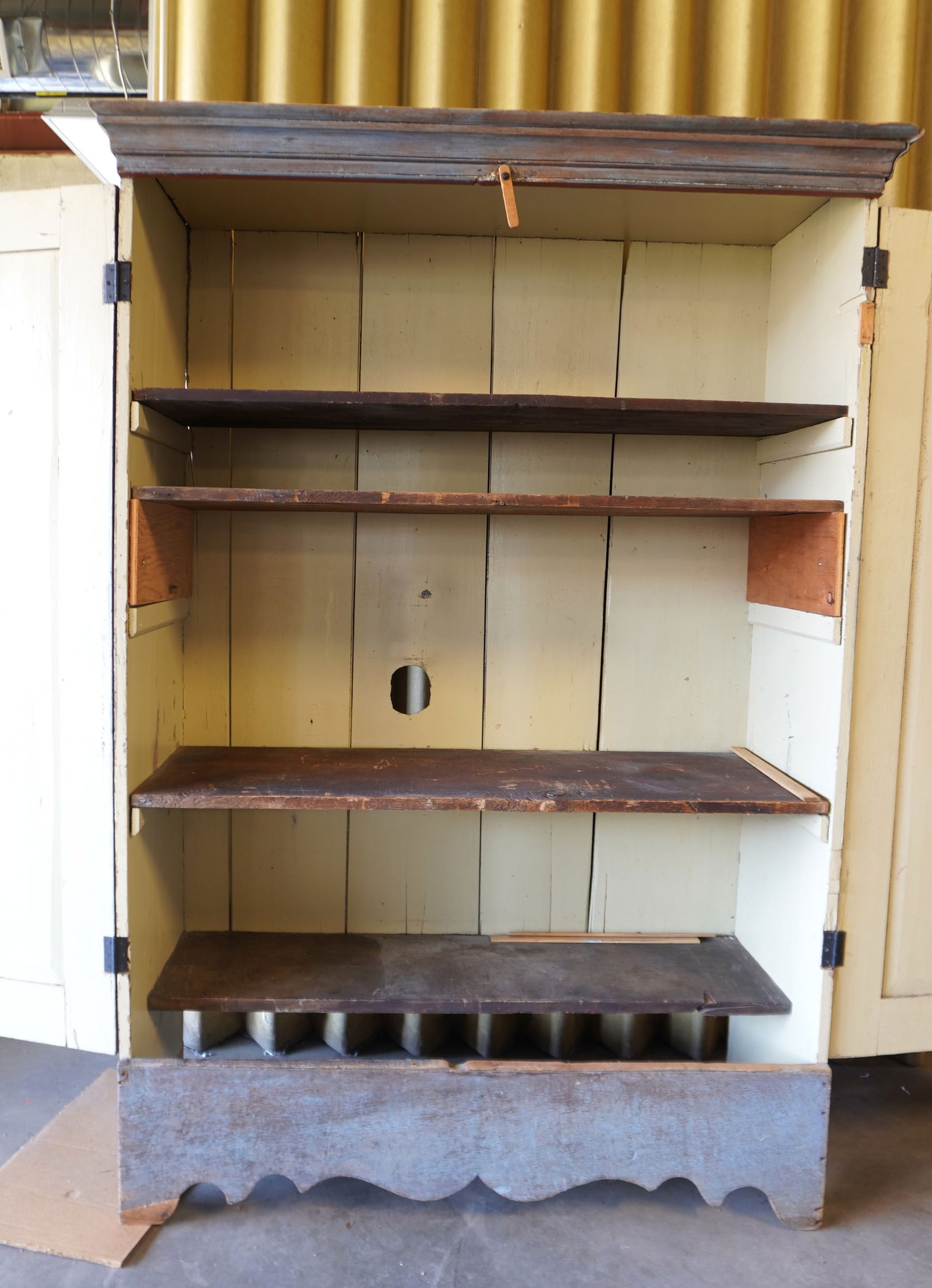 A primitive double door floor cupboard in old blue paint with a very fine scrolled front apron.: A primitive double door floor cupboard in old blue paint with a very fine scrolled front apron. Some paint touchup throughout, some restoration points including door molding, feet on both sides that n