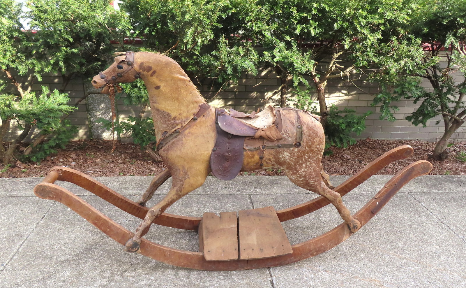 A large child's rocking horse, covered with cow hide over the carved wooden horse figure - some wear: A large child's rocking horse, covered with cow hide over the carved wooden horse figure - some wear and losses - see photos for further information. Circa 1850. Measures 72"L x 17 1/2"W x 41"H.