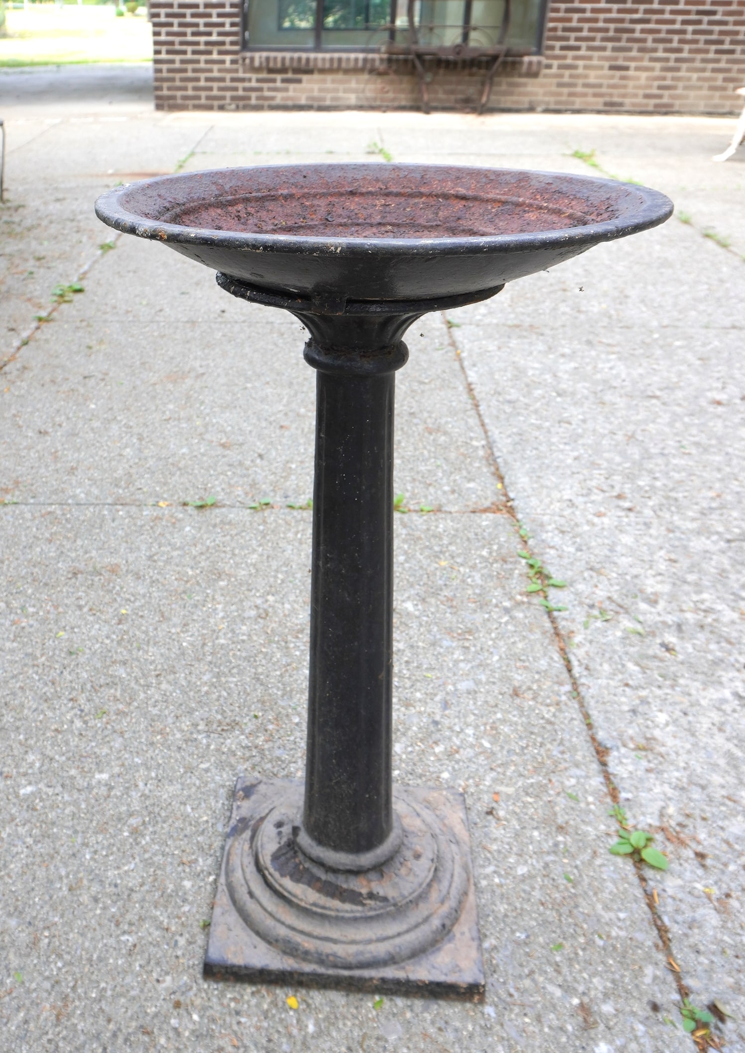 A cast iron pedestal base bird bath mounted on fluted column leading to a stepped base - in 2 parts: A cast iron pedestal base bird bath mounted on fluted column leading to a stepped base - in 2 parts (the reservoir lifts off from the column) - 19th century, traces of old black paint, some surface ru