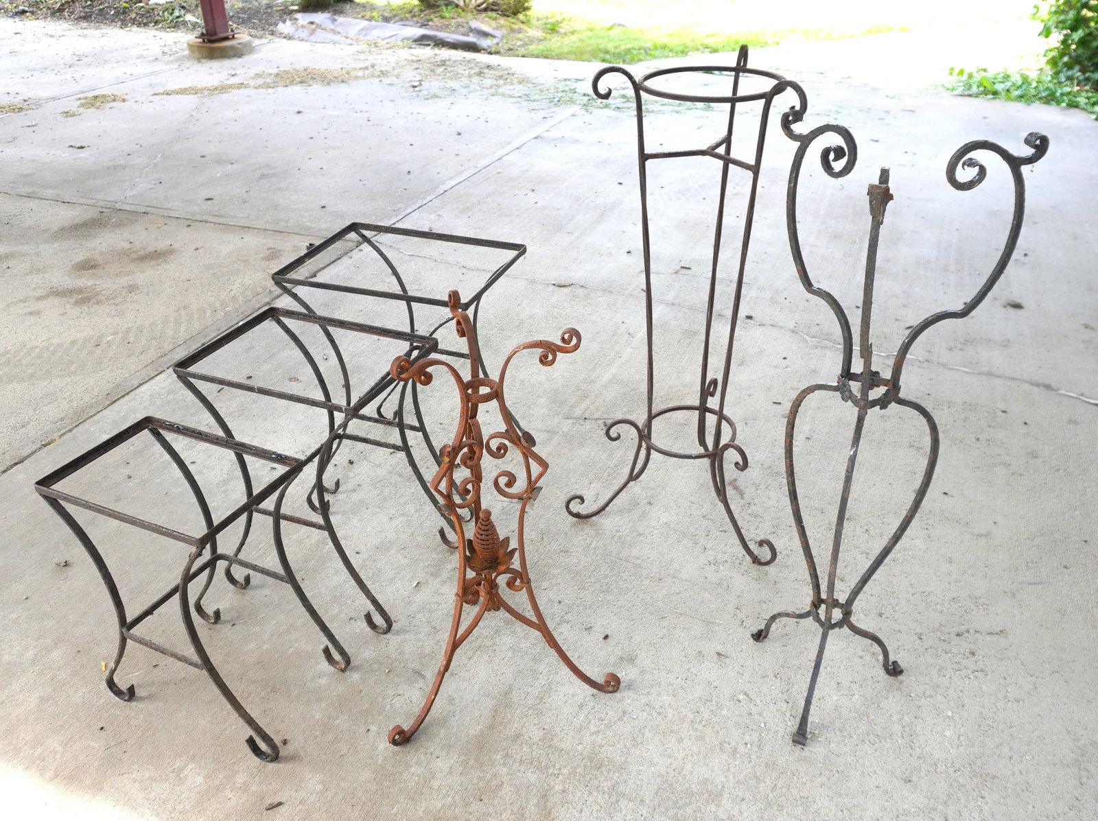 Grouping of 7 pieces of vintage garden accessories including 3 wrought iron planters (missing: Grouping of 7 pieces of vintage garden accessories including 3 wrought iron planters (missing inserts), a set of 3 wrought iron stacking tables - all missing glass inserts, and a coggled wheel shaped 