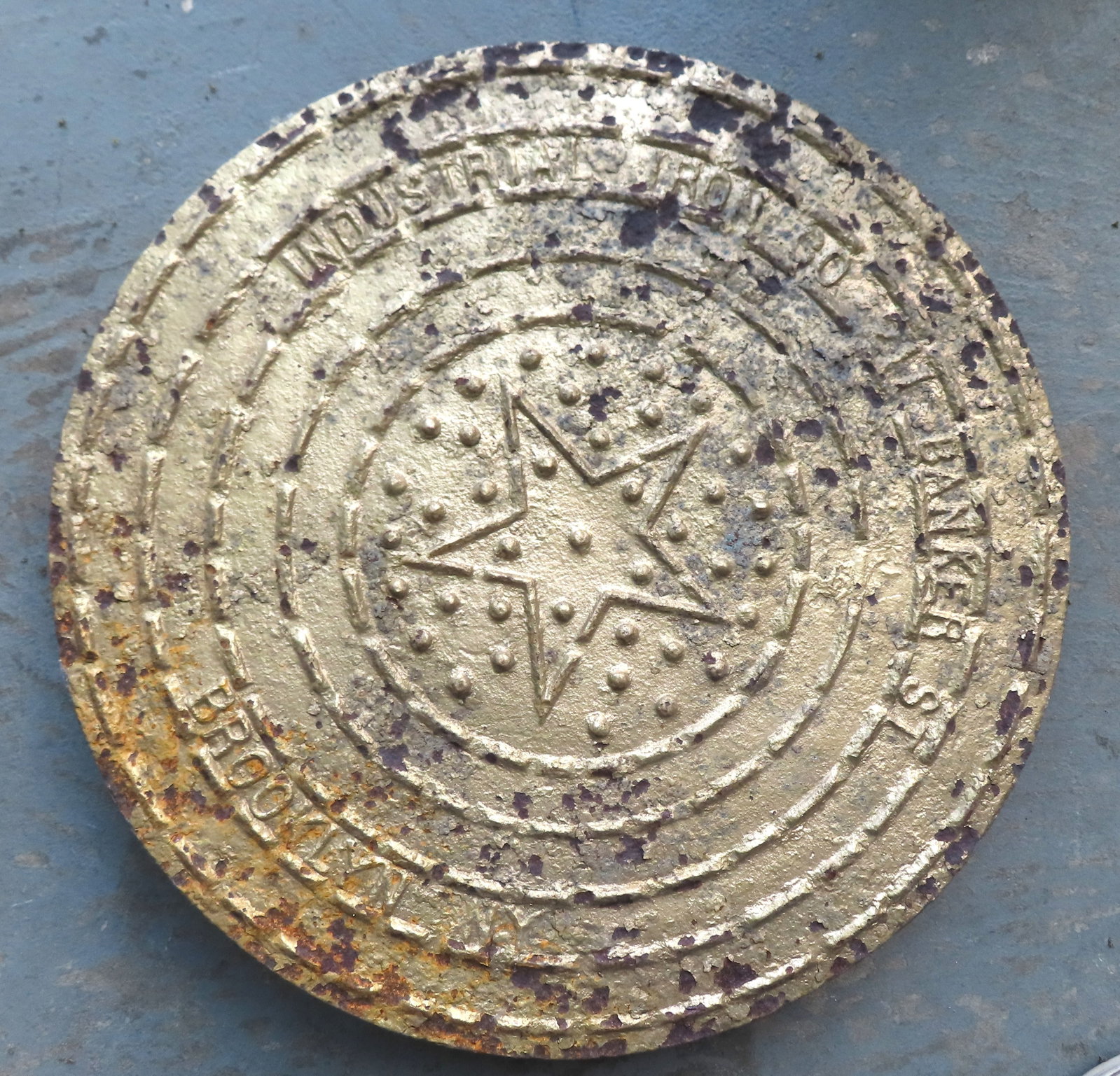 A Brookyn NY cast iron manhole cover in old gold paint, signed "Industrial Iron Co. / 211 Banker St. (1 of 2)