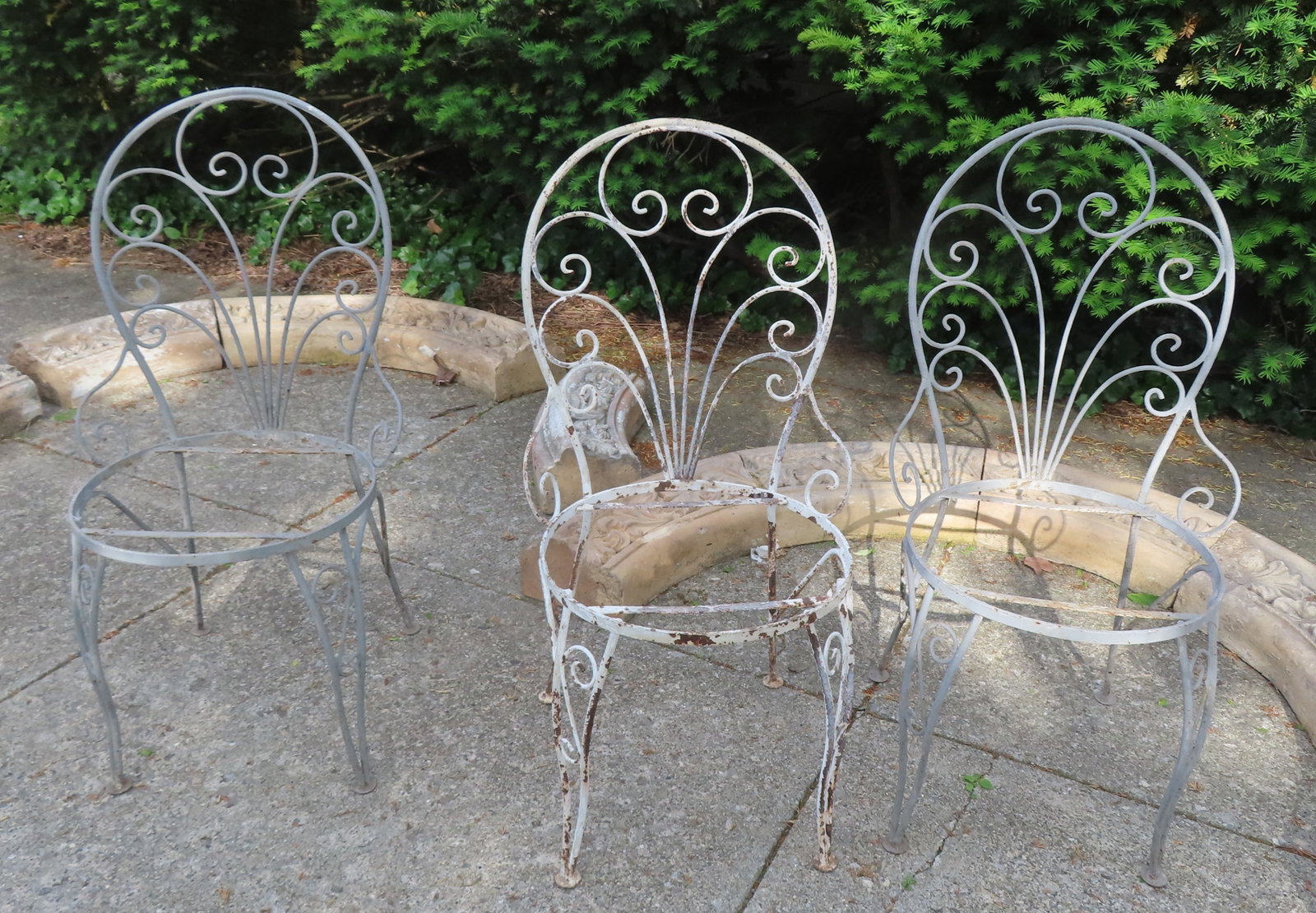 A set of 3 wrought iron garden chairs in the French style, circa 1960-70, having scrolled: A set of 3 wrought iron garden chairs in the French style, circa 1960-70, having scrolled decorations on the seat back and legs. All in old paint with some surface rust, missing seats, but overall goo