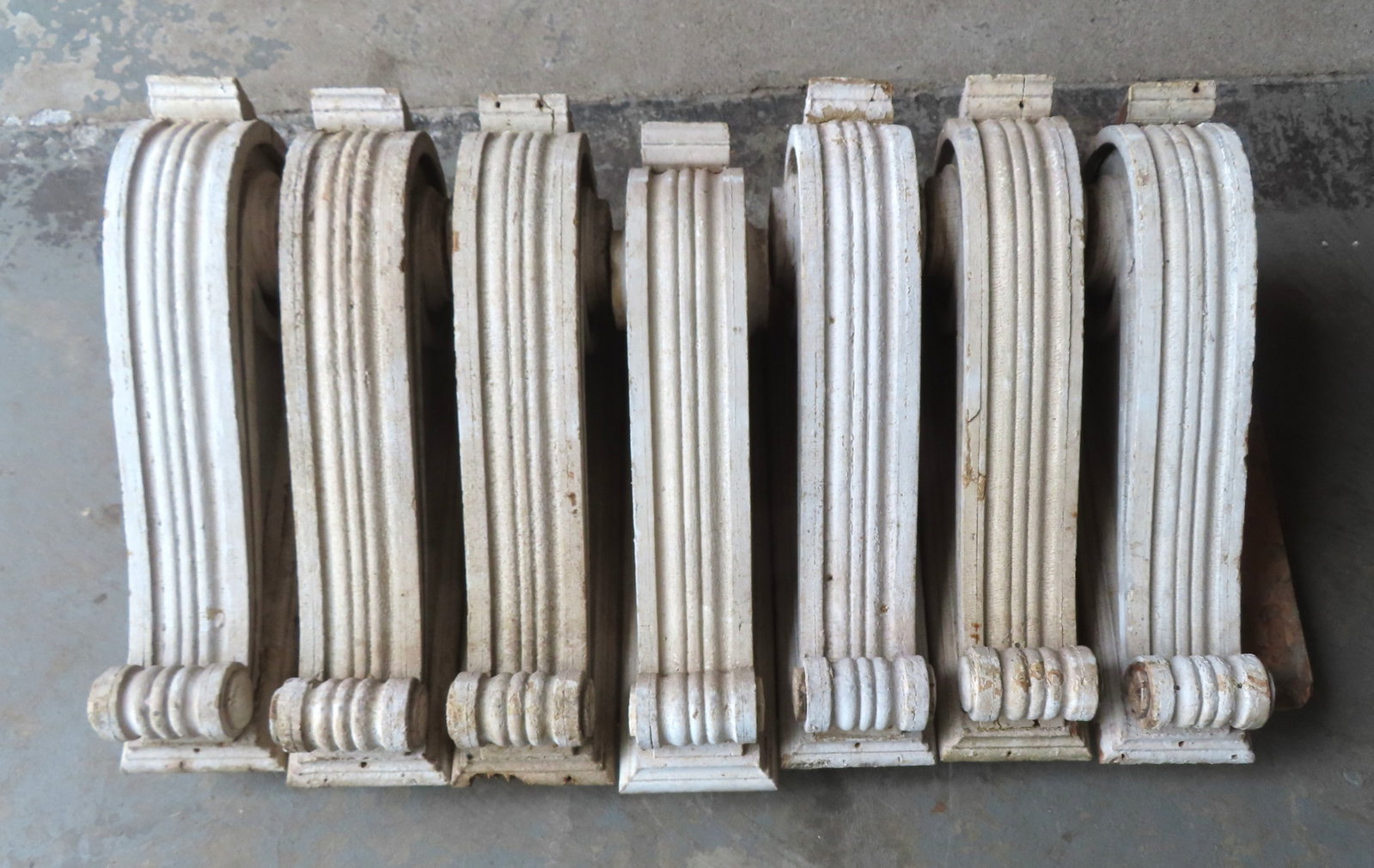 Grouping of 7 carved scroll shaped corbels, early to mid 19th century, most in very good condition: Grouping of 7 carved scroll shaped corbels, early to mid 19th century, most in very good condition with layers of old paint. All decorated with matchng scrolled and reeded tops and carved scrolled sid