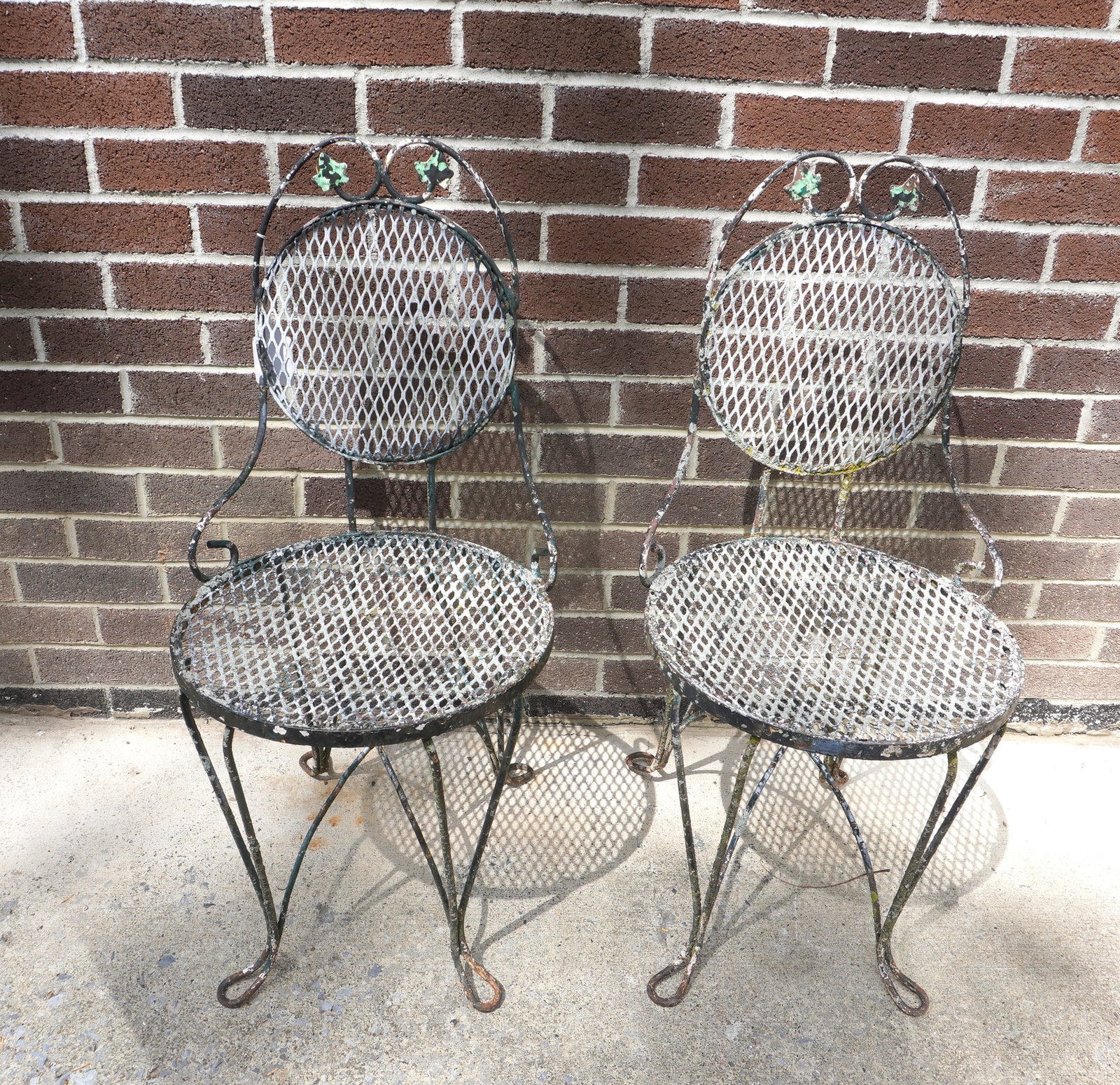 Two wrought iron patio chairs with iron mesh backs, both in old paint in good condition, circa: Two wrought iron patio chairs with iron mesh backs, both in old paint in good condition, circa 1960-70.