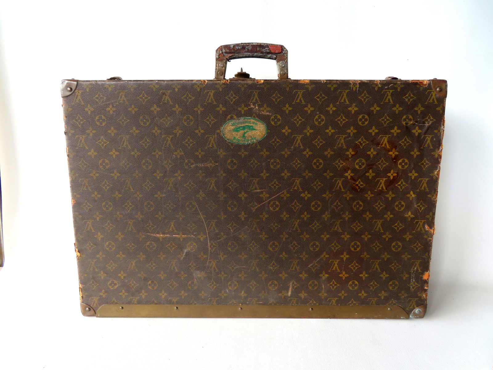 A vintage Louis Vuitton suitcase with use wear and interior taped repairs. The underside of lid with (1 of 19)