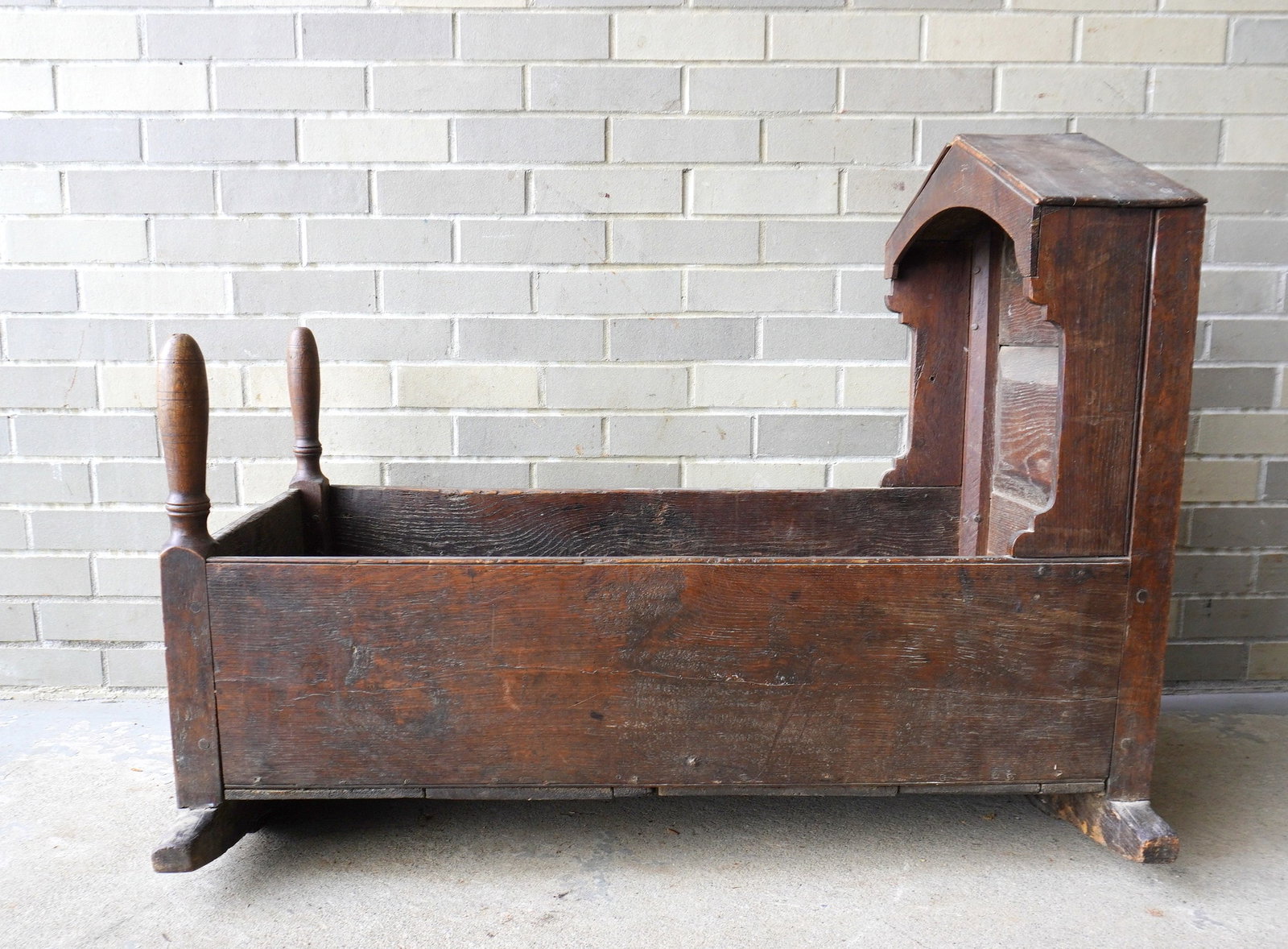 An early primitive hooded cradle with a paneled and chamfered back, early 18th century. Typical use (1 of 13)