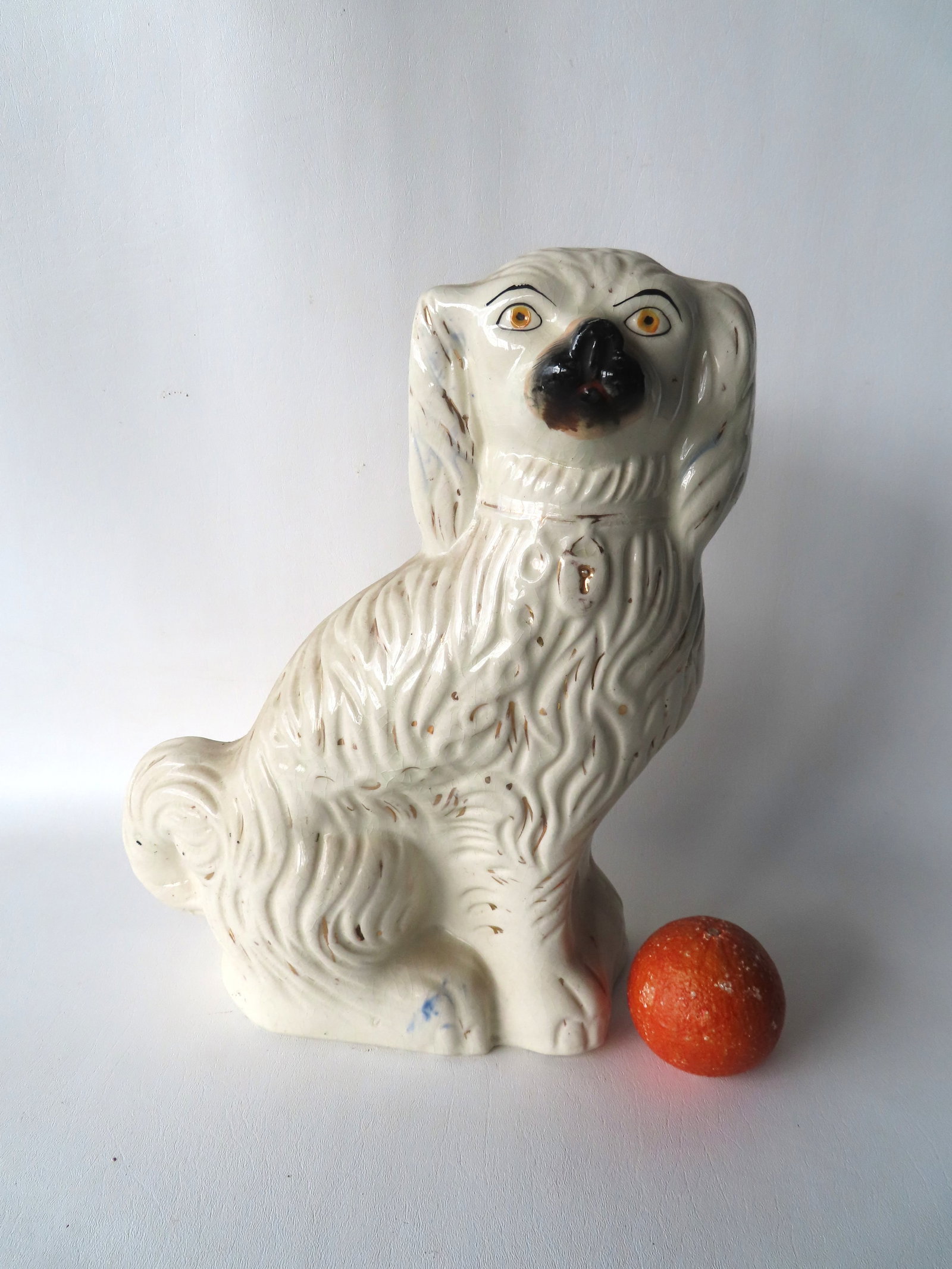 A large hand painted Staffordshire porcelain dog, 19th century. Some crazing, there appears to be a: A large hand painted Staffordshire porcelain dog, 19th century. Some crazing, there appears to be a tight hairline in underside of base but this may be part of the crazing issue, else good condition. 