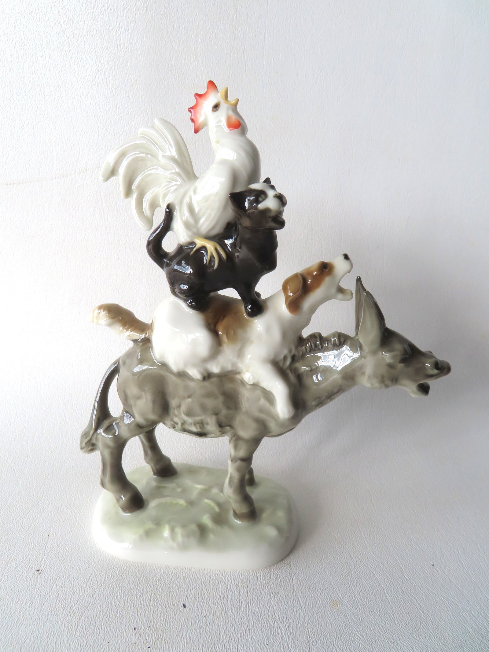 Whimsical German porcelain figurine titled "Bremen Town Musicians" depicting 4 animals stacked on: Whimsical German porcelain figurine titled "Bremen Town Musicians" depicting 4 animals stacked on top of each other with open mouths, and appearing to be singing. Signed on base "Hutschenreuther Gelb"