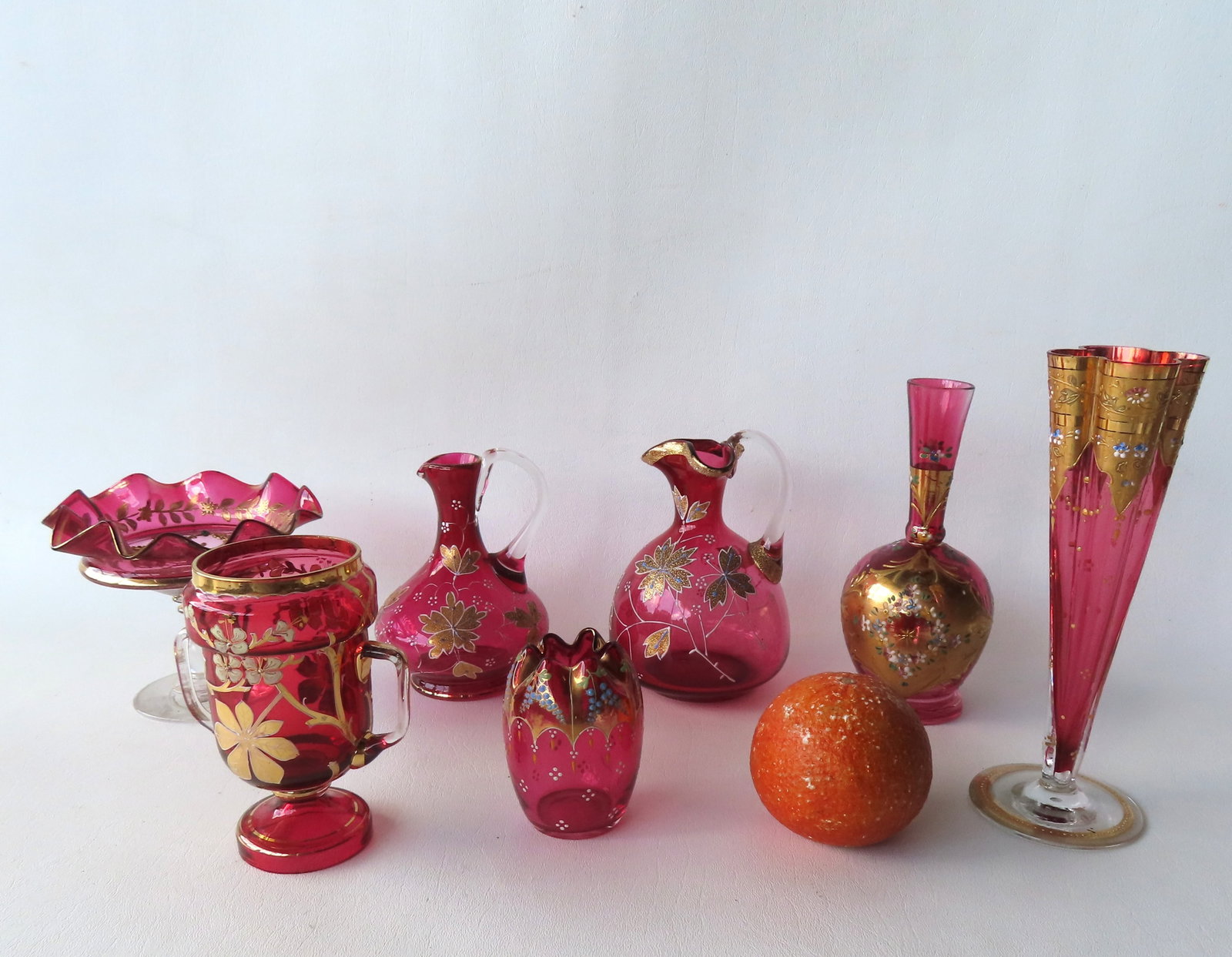 A grouping of 7 pieces of Victorian enameled cranberry glass, most hand blown. The largest, a ribbed: A grouping of 7 pieces of Victorian enameled cranberry glass, most hand blown. The largest, a ribbed vase, has a tiny flea bite on edge of rim, else very good condition - measures 8"H. The remaining 6