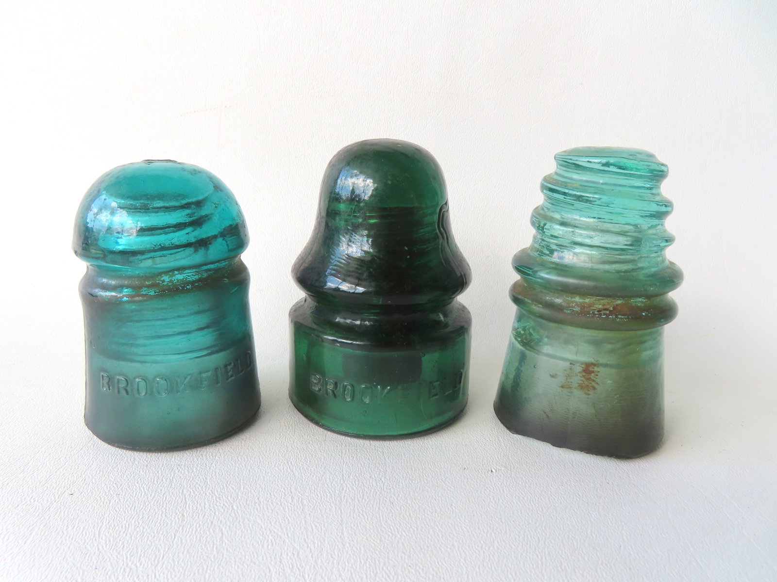 Three glass insulators including: Two signed Brookfield, one dark/emerald green with original wooden (1 of 7)