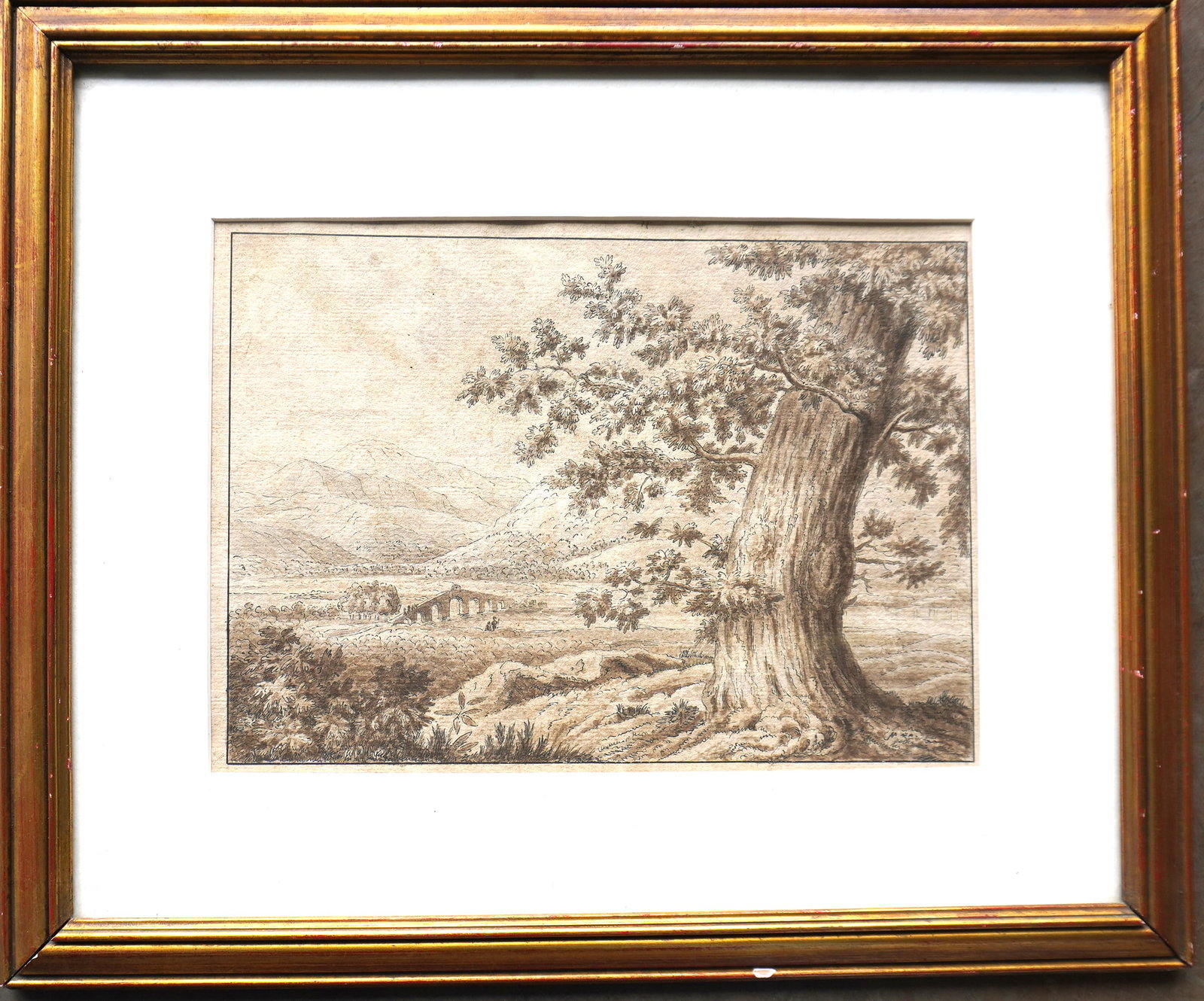 W/C Landscape of a large tree in foreground and bridge, figures by river, and mountains in: W/C Landscape of a large tree in foreground and bridge, figures by river, and mountains in background, probably late 19th century - not signed - professionally framed and matted in a 20th century