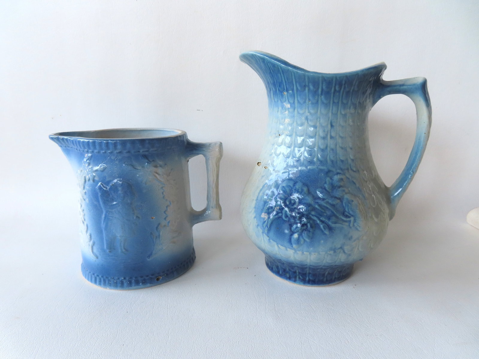 Two stoneware blue and white pitchers. One decorated with embossed flowers and the other decorated (1 of 4)