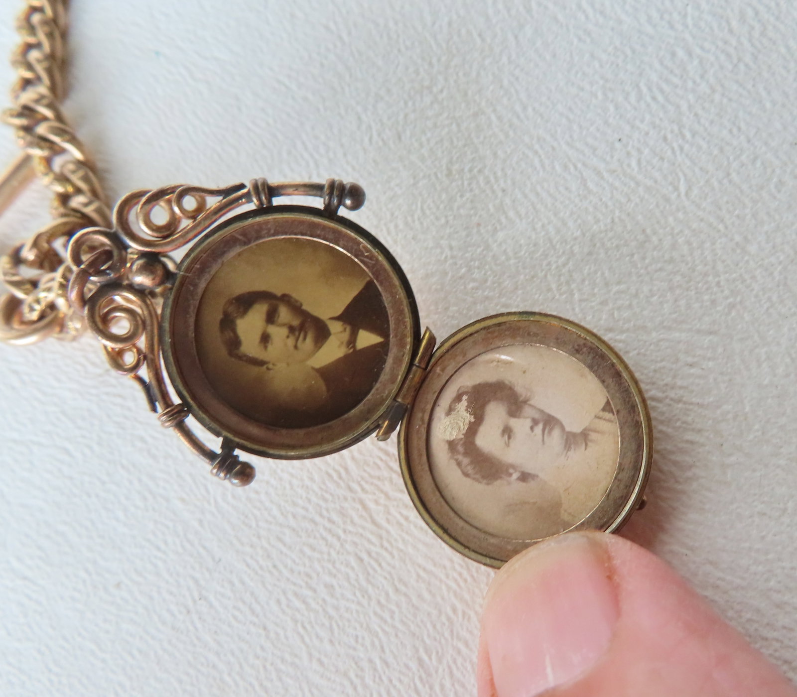 An ornate gold double locket, marked 10k, housing photographs of husband and wife from the Edwardian: An ornate gold double locket, marked 10k, housing photographs of husband and wife from the Edwardian period - attached to a gold filled chain (watch fob) marked H & H (Hamilton & Hamilton), probably l