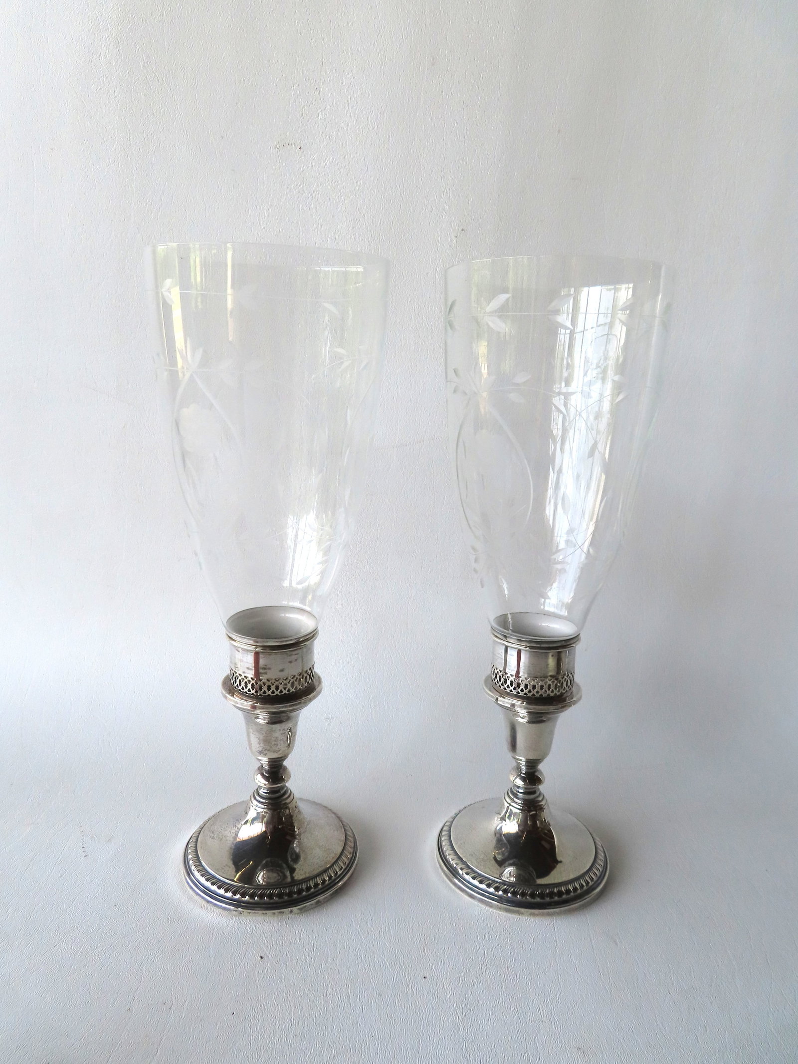 A matched pair of sterling silver hurricane lamps, weighted, signed Towle. The glass shades etched: A matched pair of sterling silver hurricane lamps, weighted, signed Towle. The glass shades etched with flowers and leaves on vines, probably early to mid 20th century. The lamps without shades measur