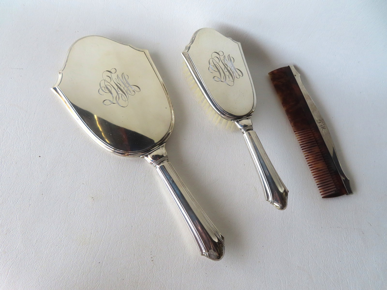 A 3 piece sterling dresser set consisting of mirror, hair brush and comb, each piece with monogram. (1 of 3)
