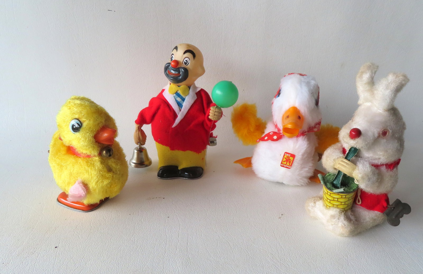 Four Japanese/German articulated windup toys including: Clown ringing bell holding balloon - Japan;: Four Japanese/German articulated windup toys including: Clown ringing bell holding balloon - Japan; rabbit eating vegetable from pail - Japan; walking duckling - Japan; and a swimming mother duck with