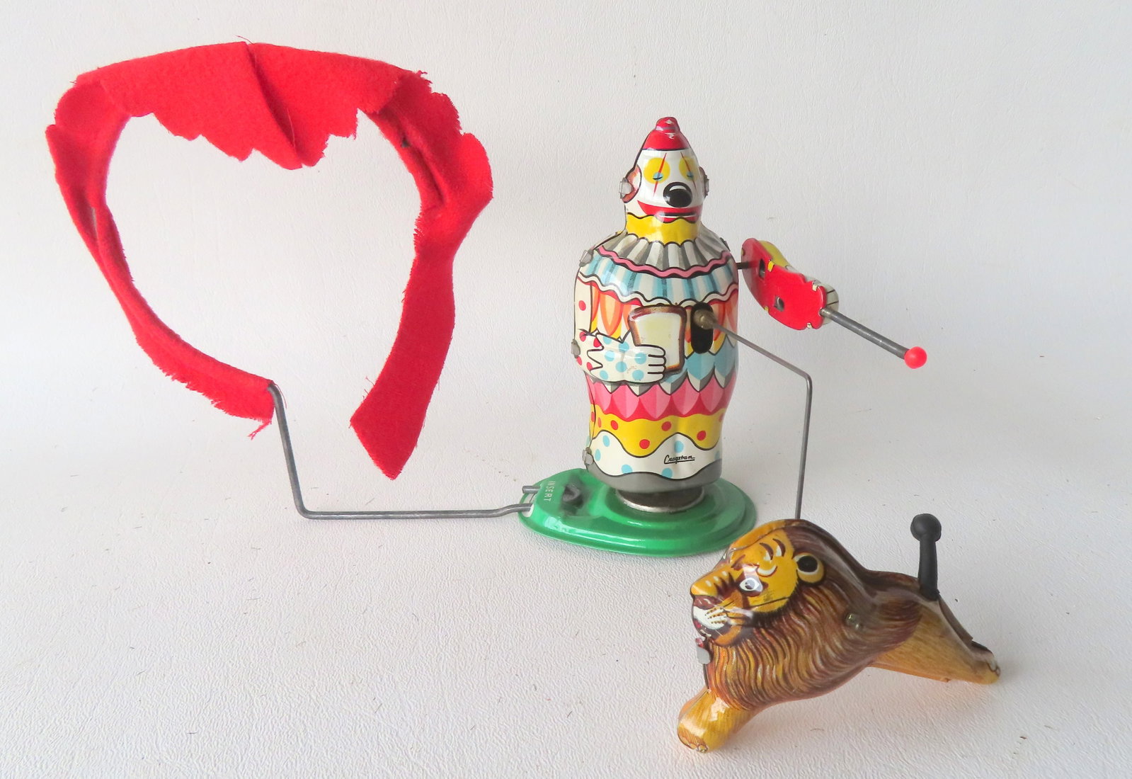 A Japanese lithograph windup clown leading lion through burning hoop toy, signed T.P.S. Made in (1 of 4)