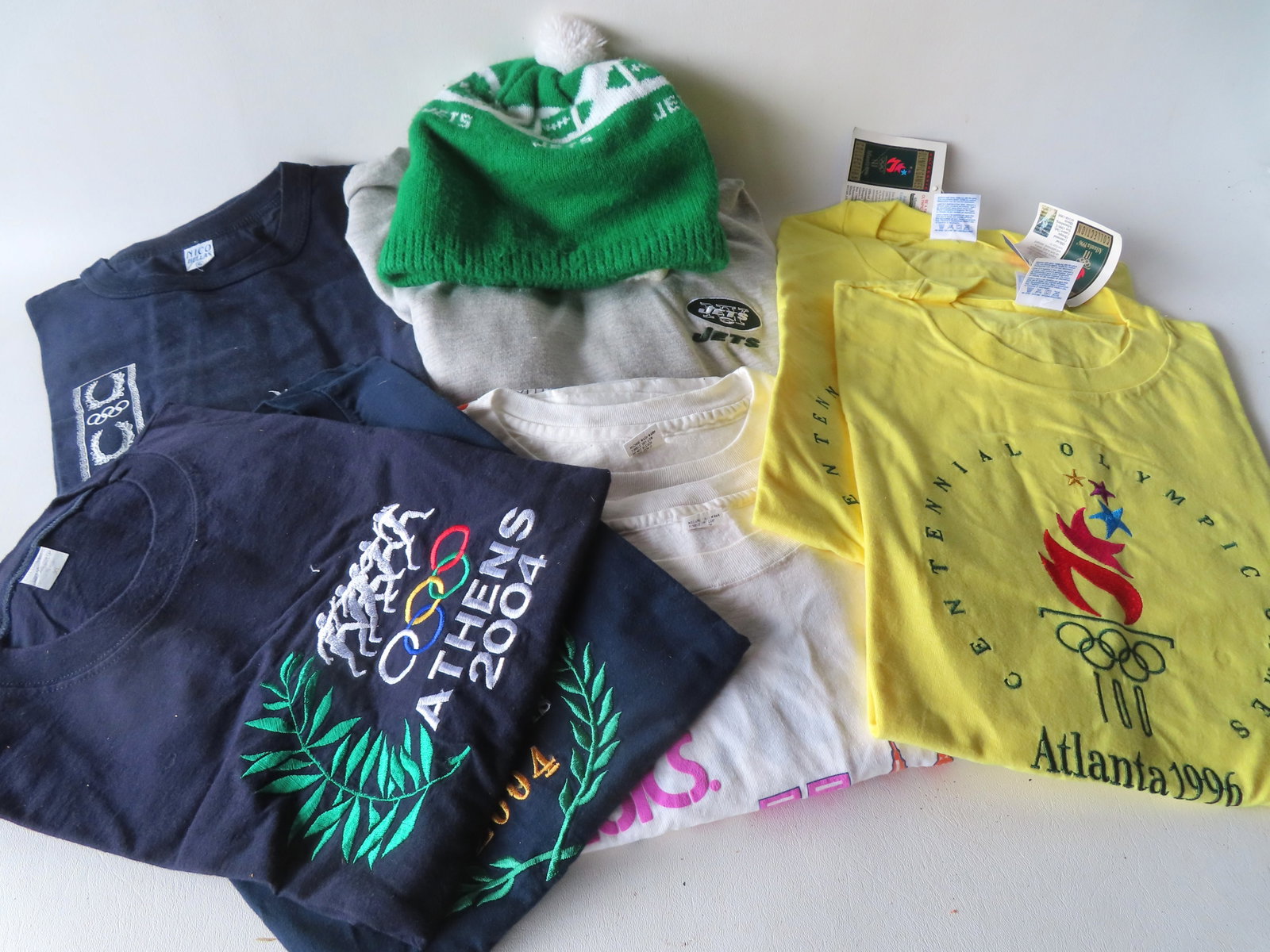 Grouping of 8 track and field related tea shirts from late 20th to early 21st century. All size XL,: Grouping of 8 track and field related tea shirts from late 20th to early 21st century. All size XL, an appear unused in excellent condition. Together with 2 NY Jets winter pull over hats and a NY Jets