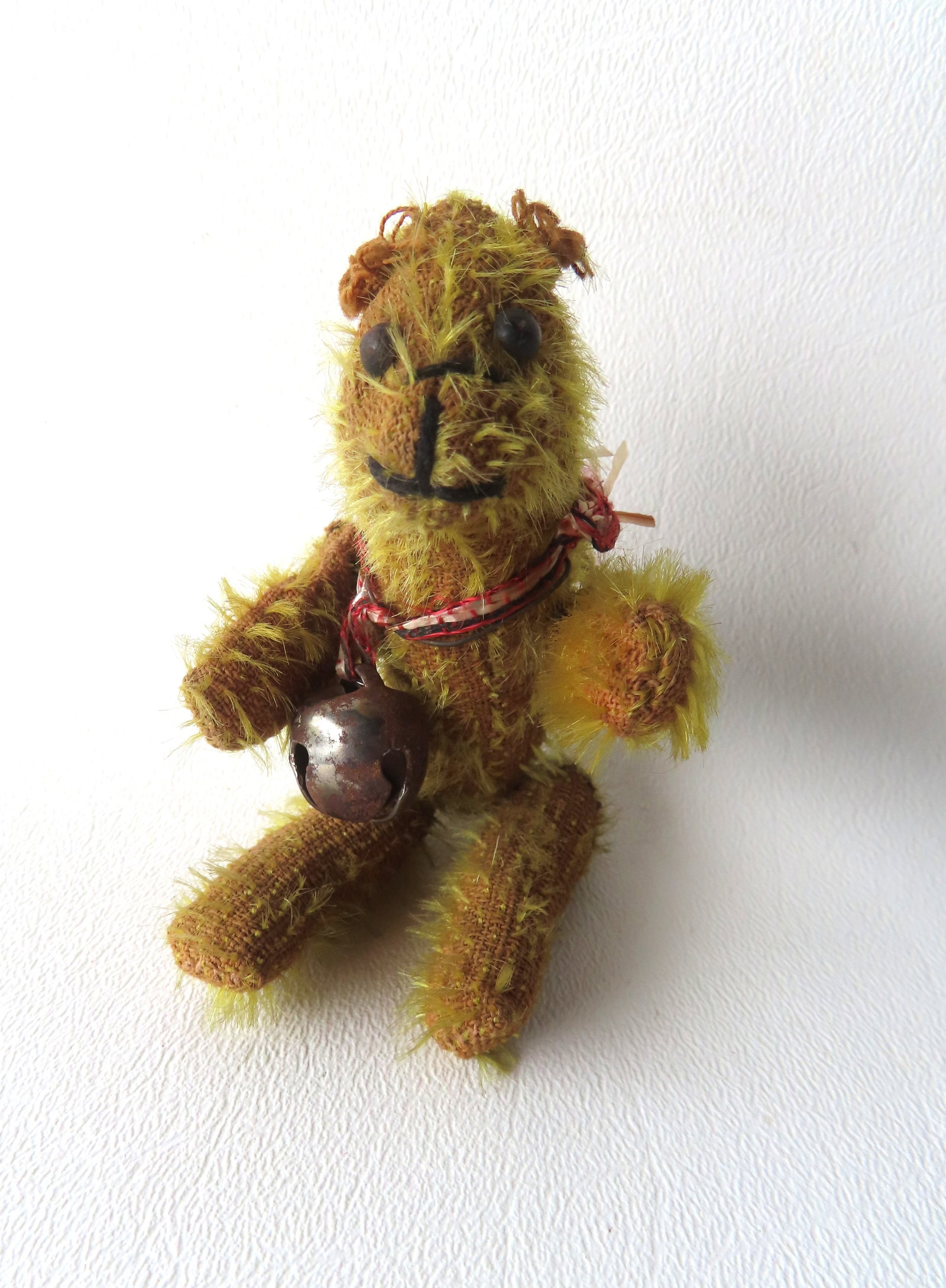 A scarce miniature jointed mohair Teddy bear with shoe button eyes which appear to be original: A scarce miniature jointed mohair Teddy bear with shoe button eyes which appear to be original, with hand sewn seams, probably late 19th century, unknown maker, later bell added to neck. Losses to moh
